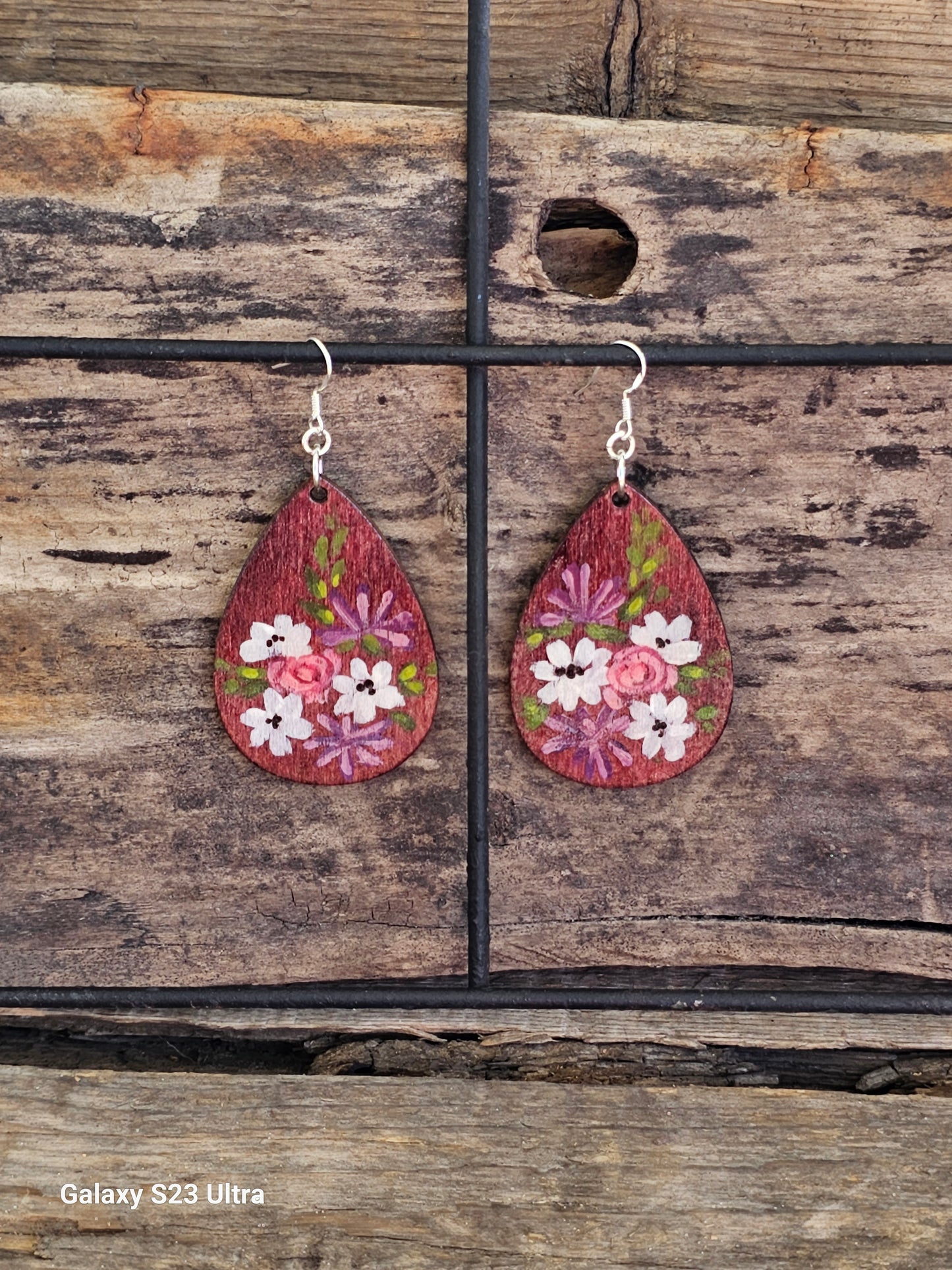 Hand Painted Ultra Lightweight Wooden Earrings. Watercolor and Acrylic. Plum colored background. Muted white lilies, pink roses, purple chrysanthemums design. Teardrop in shape. Back is painted in complimentary color. Sterling Silver Findings. Hangs 2 1/4" in Length