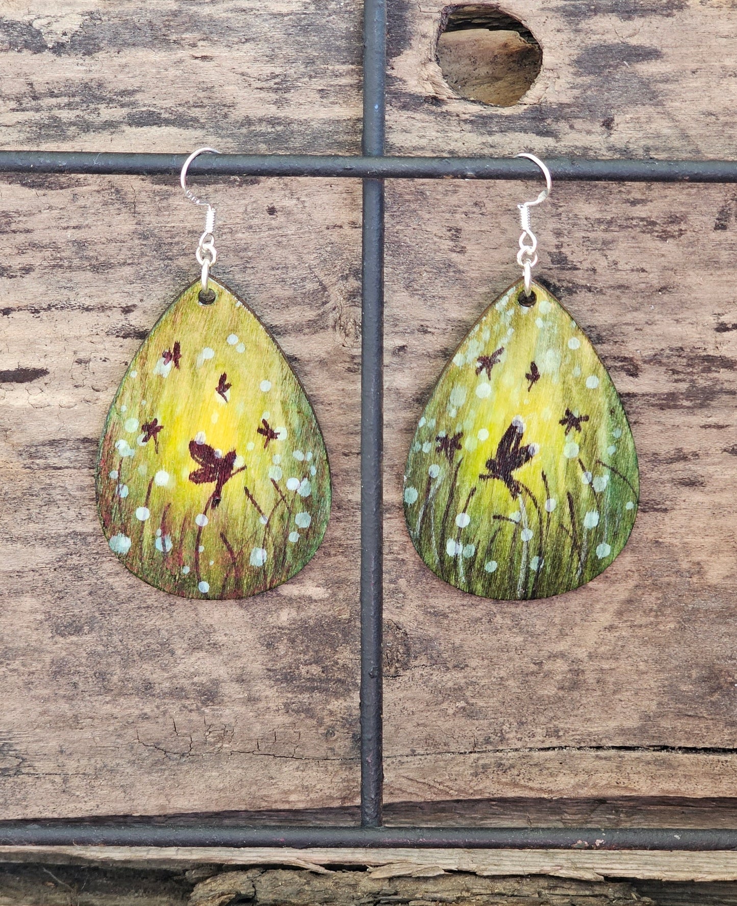 Hand Painted Ultra Lightweight Wooden Earrings. Watercolor and Acrylic. Multi toned Green colored background. Dragonfly Fairies, Mystical Forest . Teardrop in shape. Back is painted in complimentary color. Sterling Silver Findings. Hangs 2 1/4" in Length