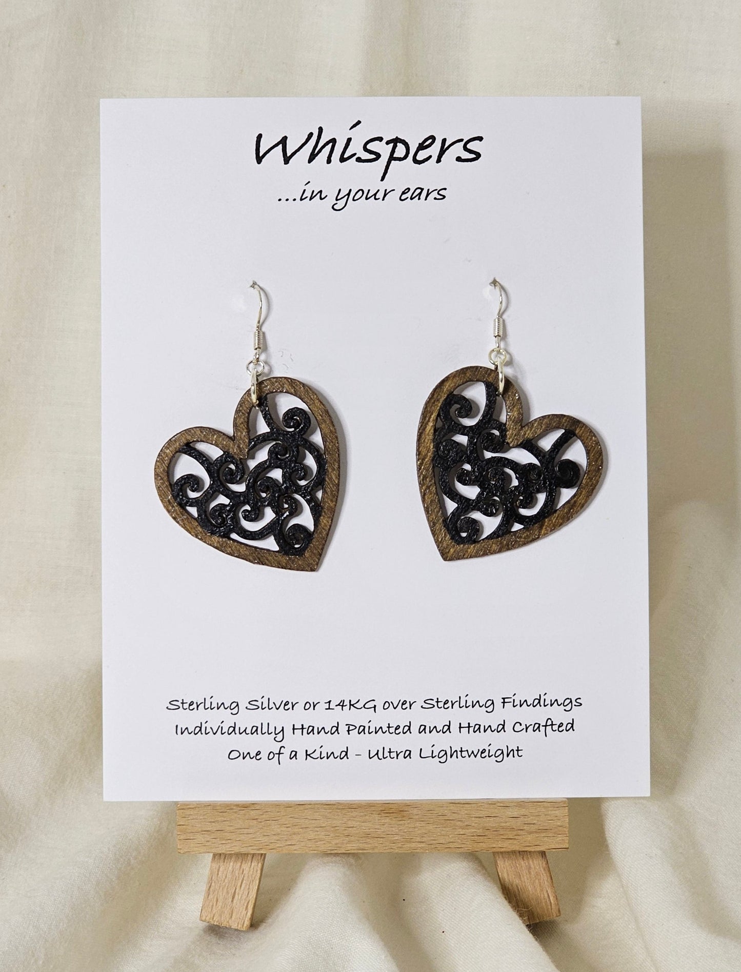 Heart Earrings Wood die cut hand painted. Walnut tone wood heart shape with black faux metal filigree pattern. Enameled for durability. Back is painted in the same color and pattern. Heart is 1 1/2 " in width. Sterling silver findings. Hangs 1 1/2" in length