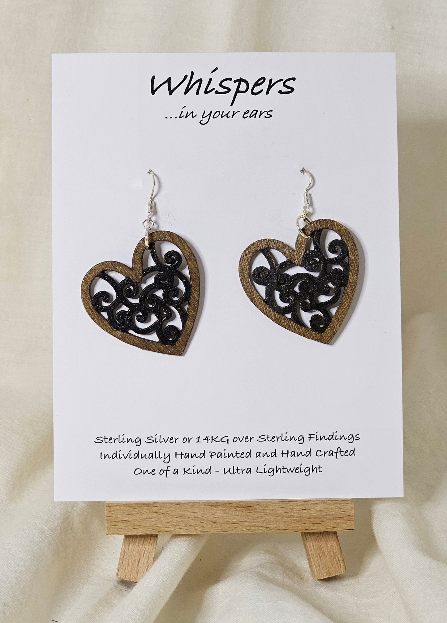 Heart Earrings Wood die cut hand painted. Walnut tone wood heart shape with black faux metal filigree pattern. Enameled for durability. Back is painted in the same color and pattern. Heart is 1 1/2 " in width. Sterling silver findings. Hangs 1 1/2" in length