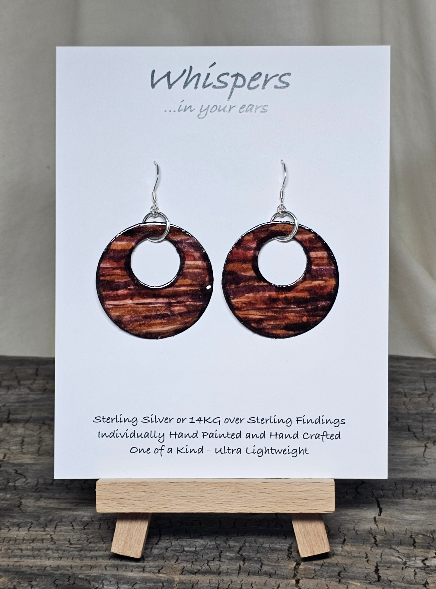 Rustic Faux Wood Circles Hand Painted Paper Earrings. Dark and medium brown in watercolor. Espresso painted edge detail. 1 1/2" Circular in shape with circular cut out. Sterling Silver findings. Hangs 1 3/4" in length