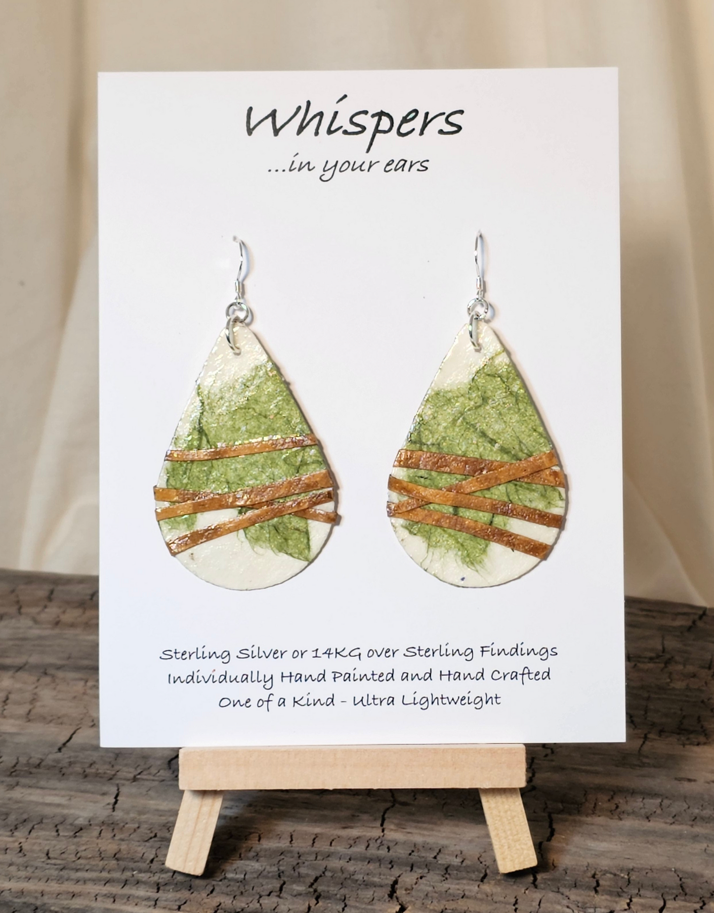 Off White and Green Faux Leather Wrapped Handcrafted Paper Earrings. Ultra lightweight. Created from handmade papers. Various shades of green. Faux leather strap wrap. Back is the same colors and design. 2" Tear drop shape. Sterling silver findings. Hangs 2 1/2" in length