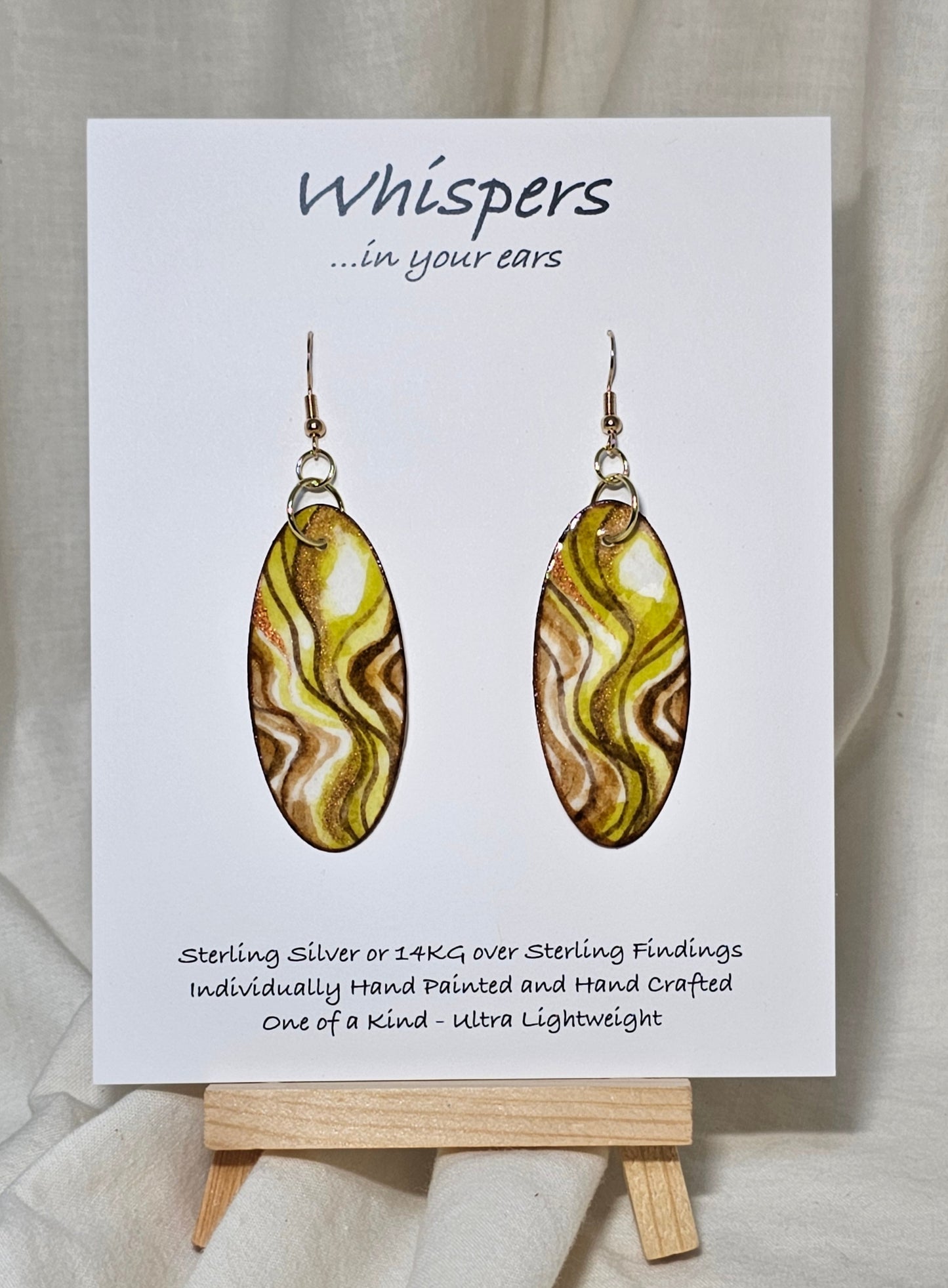 Hand Painted Watercolor Paper Earrings. 2" Elongated oval, lime and moss greens accented with tans and browns in color. Copper Metallic accents. Back is painted in complimentary design. Resin coating for durability. 14KG over sterling silver findings. Hangs 2 1/4"