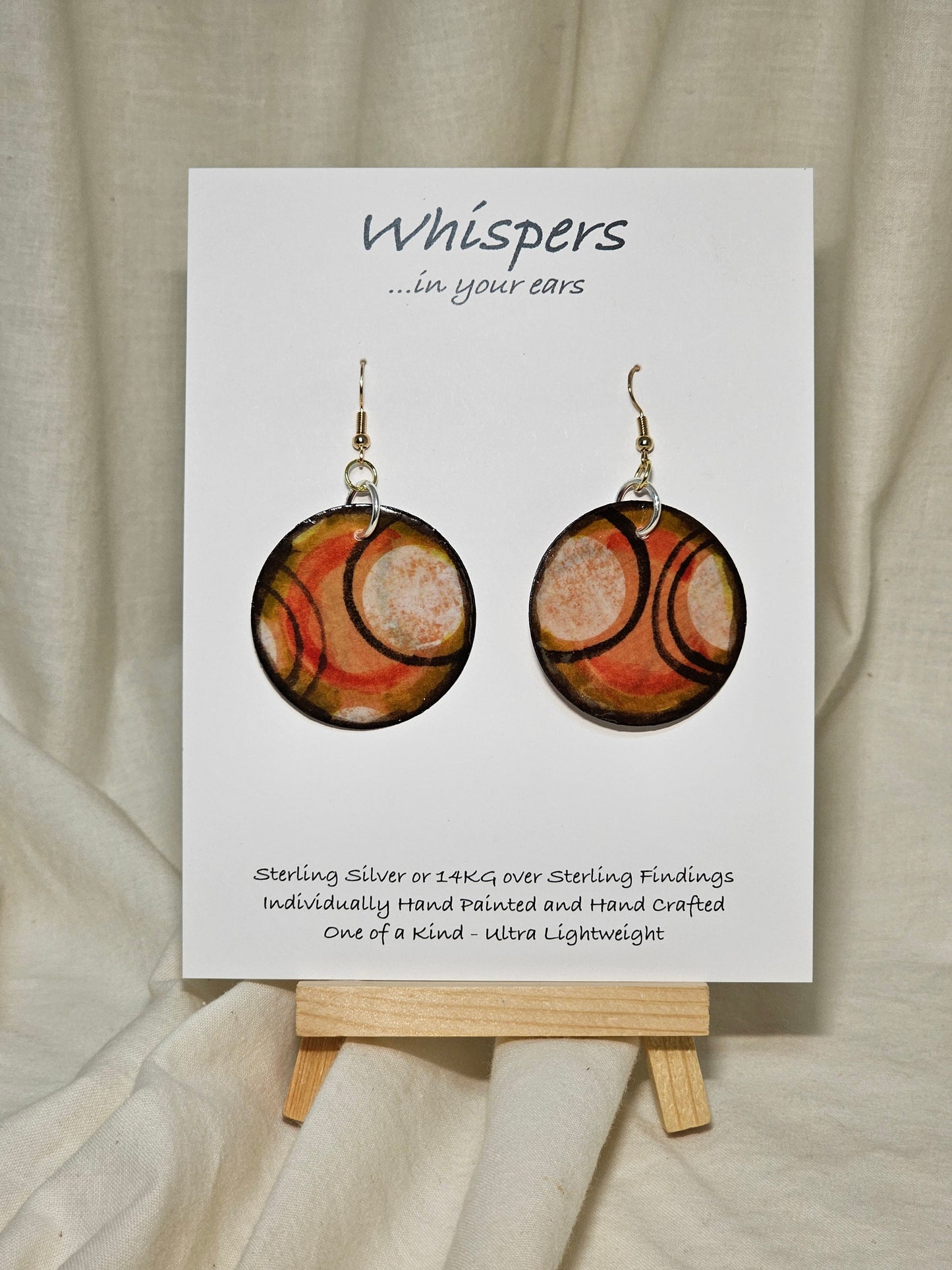 Hand painted Paper earrings. Embellished with acrylics. Look of white dot with black, orange and red lines. Back of earring is painted to match. Ultra lightweight. Resin coated for durability. 1 1/2 in diameter Mix metals Sterling Silver and 14KG over Sterling findings. Hangs 1 3/4" in length