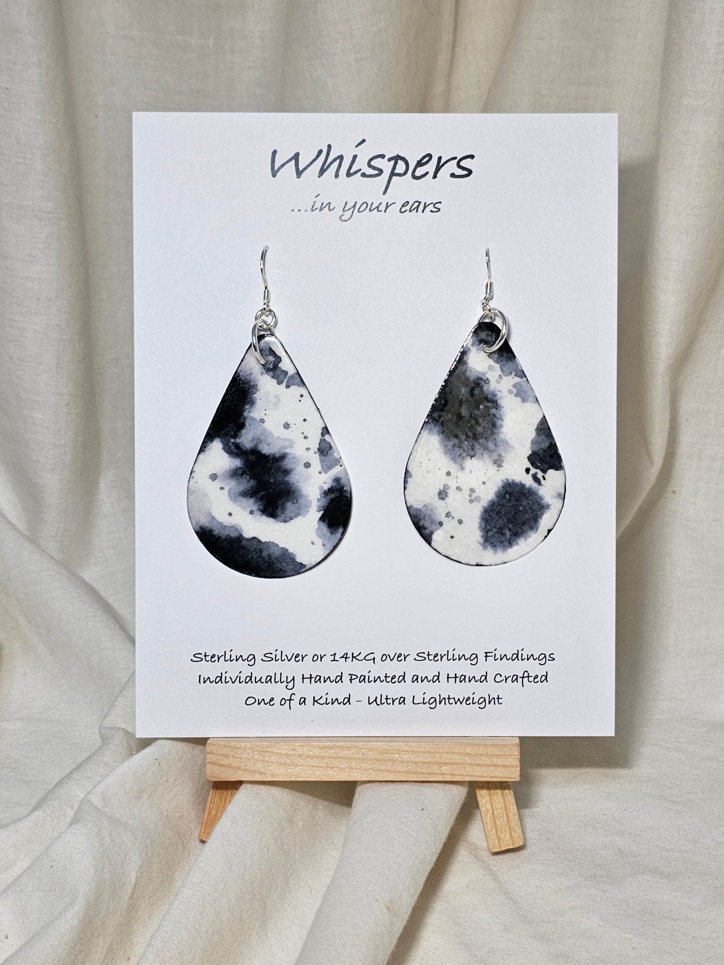 Black Cow Hide hand painted watercolor paper earrings. Ultra lightweight, 2 1/8" Tear Drop. Back is painted to match. Resin coating for durability. Sterling Silver findings. Hangs 2 1/2" in length.
