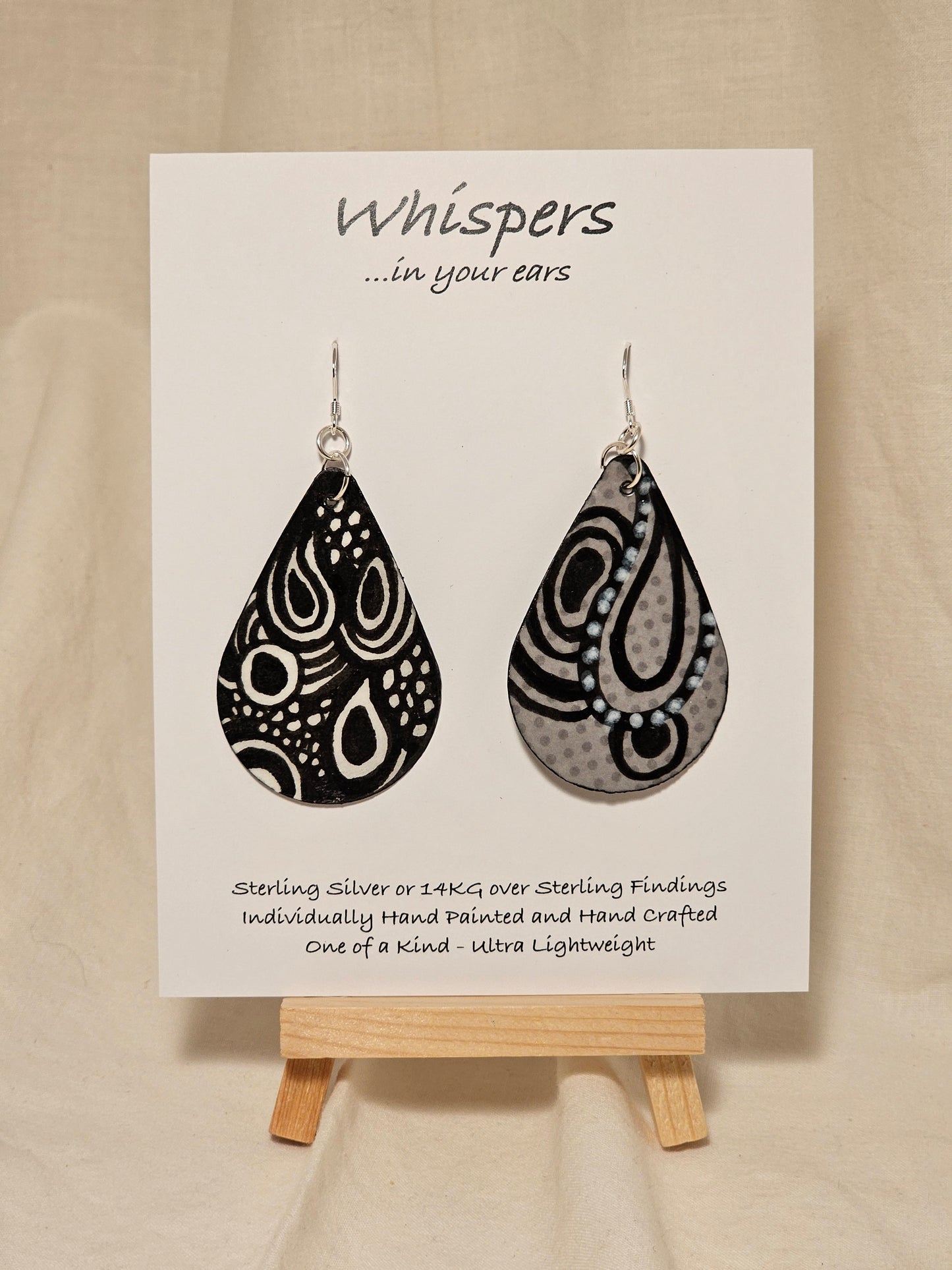 Black n White Swirls n Dots and Painted Paper Earrings. 2 1/8" Tear Drop shape. Abstract white swirls on black background. Back is Grey dots and similar design. Resin coating for durability. Sterling silver findings. Hangs 2 1/2" in length