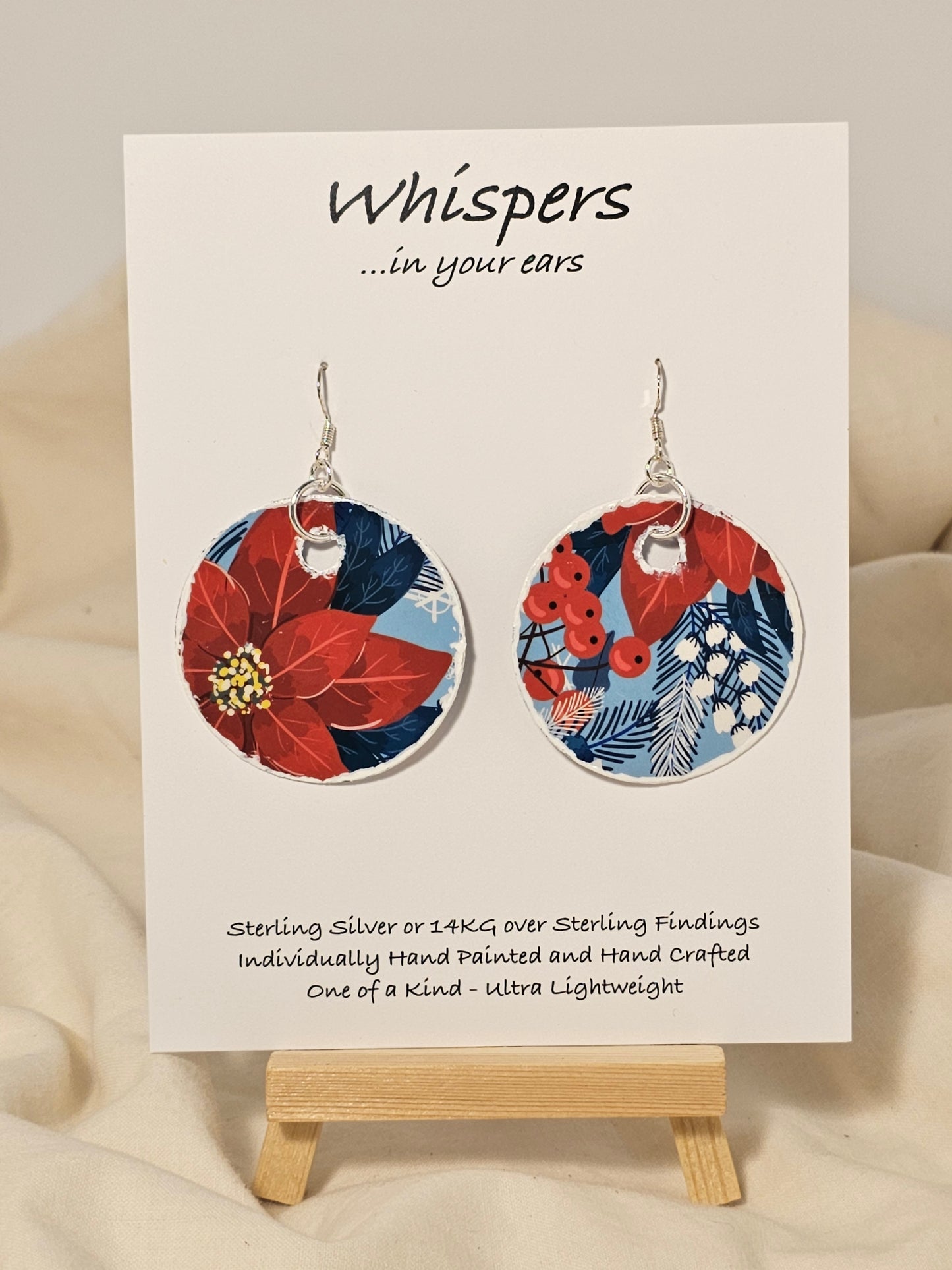 Poinsettia Embossed Repurposed Card Paper Earrings. 1 3/4" Circle edge painted and embellished with white texture. Back is complimentary design. Resin coating for durability. Sterling Silver findings. Hangs 2" in length