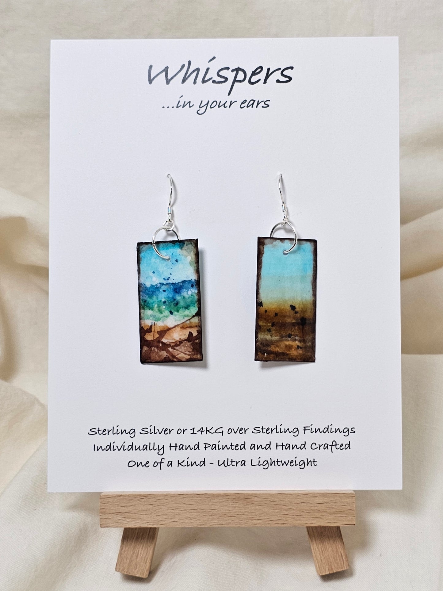 Blowing Ocean Scape Hand Painted Paper Earrings. Ultra lightweight ! 1/2" Rectangle painted in watercolor. Abstract ocean scape. Aqua, blues and browns. Back is painted similar design. Resin coating for durability. Sterling silver findings. Hangs 1 3/4" in length