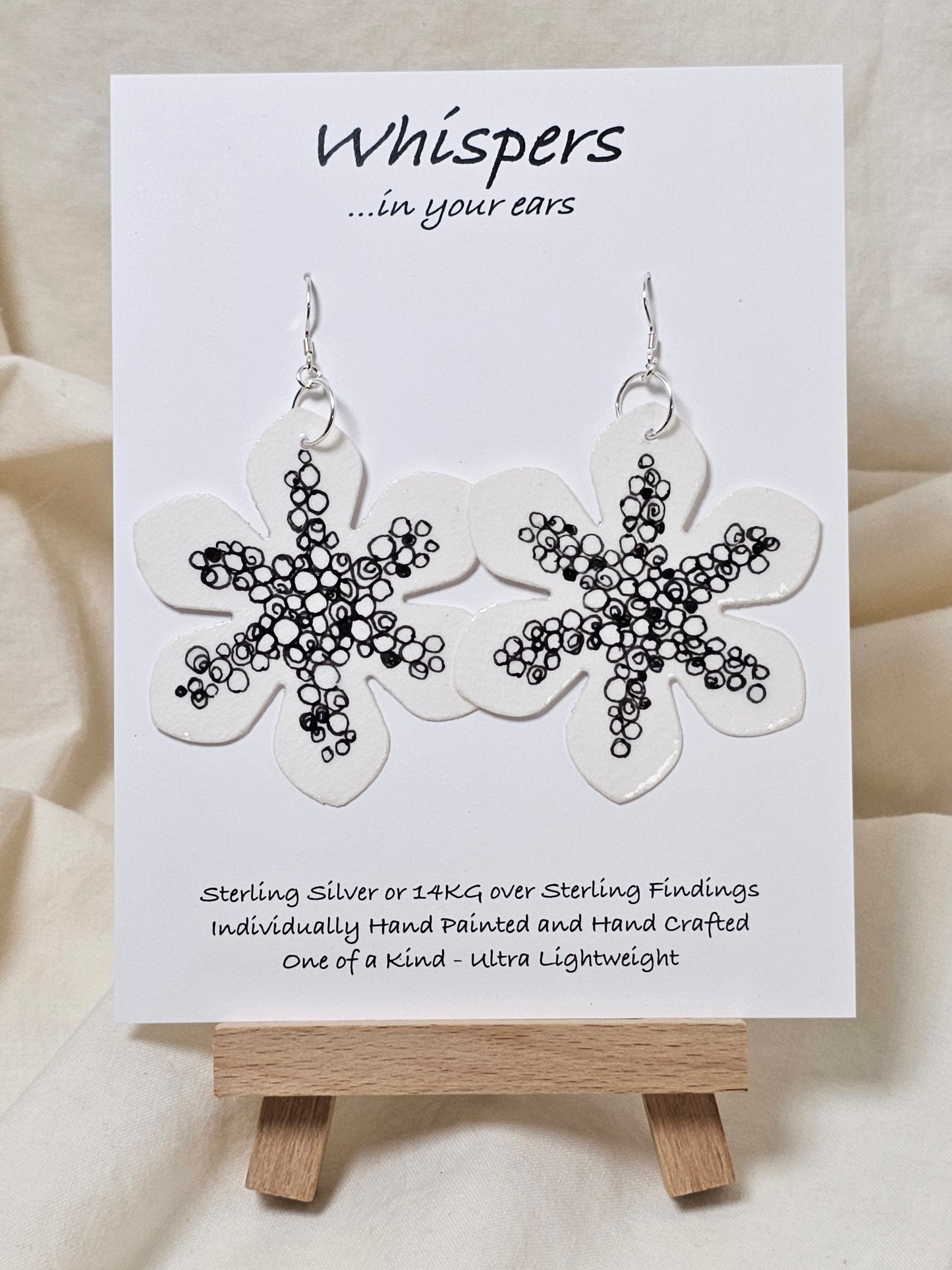 Interconnection in Black and White Flower Hand Painted Paper Earrings. Ultra lightweight 2 1/2" in diameter. Watercolor painted to resemble bright white flower with numerous interconnecting circles and swirls. Back is painted with same design. Resin coating for durability. Sterling Silver findings. Hangs 2 5/8" in length