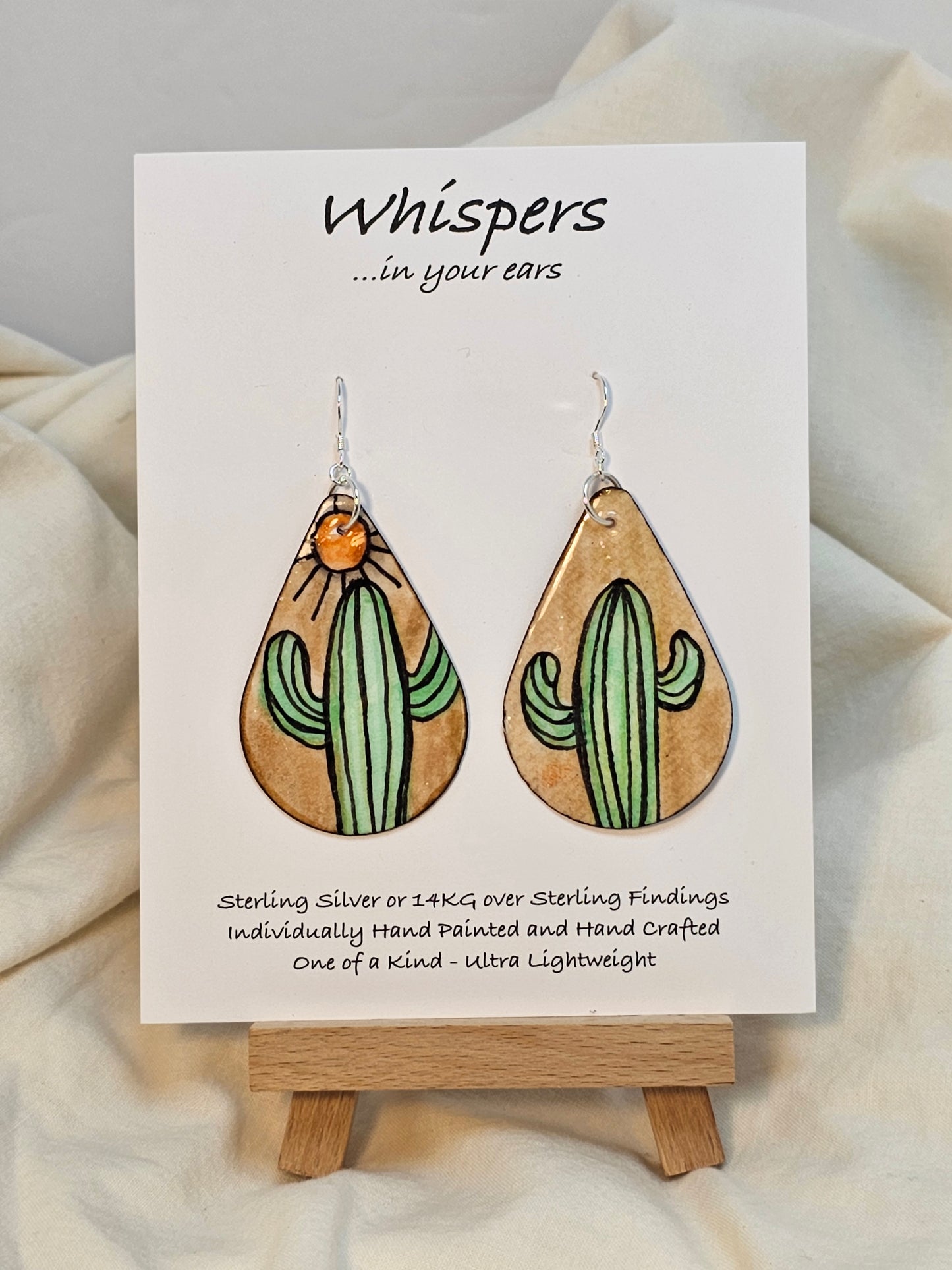 Sunburst Cactus hand painted watercolor paper earrings. Ultra lightweight. Tans and Muted greens. Dark brown edge detail. Back is painted with similar colors and design. Tear drop in shape. Resin coating for durability. Sterling silver findings. Hangs 2 1/4" in length