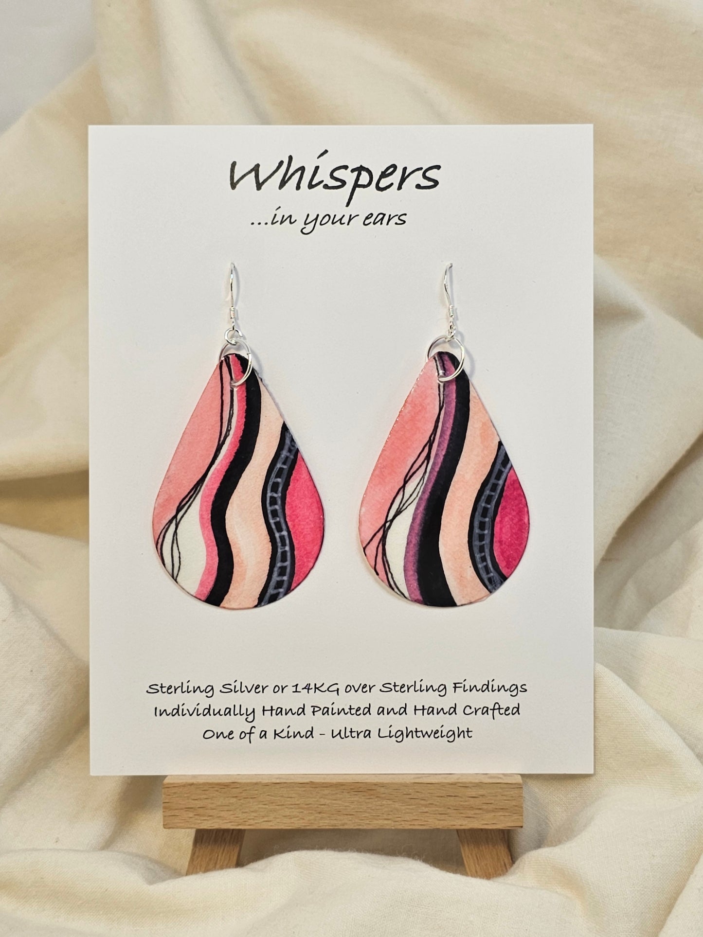 Fifties Flare hand painted watercolor ultra lightweight paper earrings. 2" Teardrop shape painted in hot pink and coral pink gem tones. Accented with black and white varied wavy lines. Back is painted with similar colors and design. Resin coating for durability. Sterling silver findings. Hangs 2 1/4" in Length