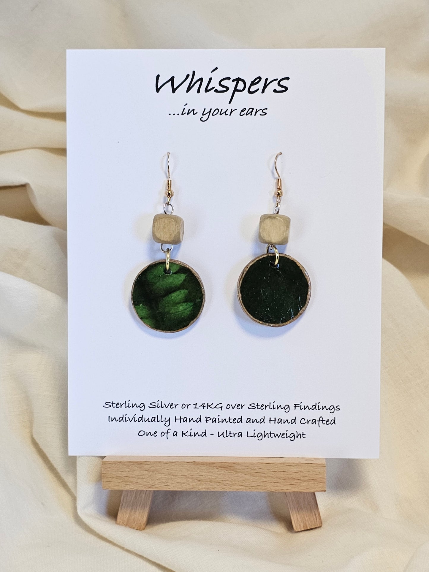 Leaf Relief Hand Crafted Wood Earrings. 1" Wood Disc with two tone green handmade paper painted gold edges and hanging from cream colored square wooden bead. Resin Coating for durability. Back is done to compliment. 14kg over sterling ear wire sterling silver findings. Hangs 1 3/4"