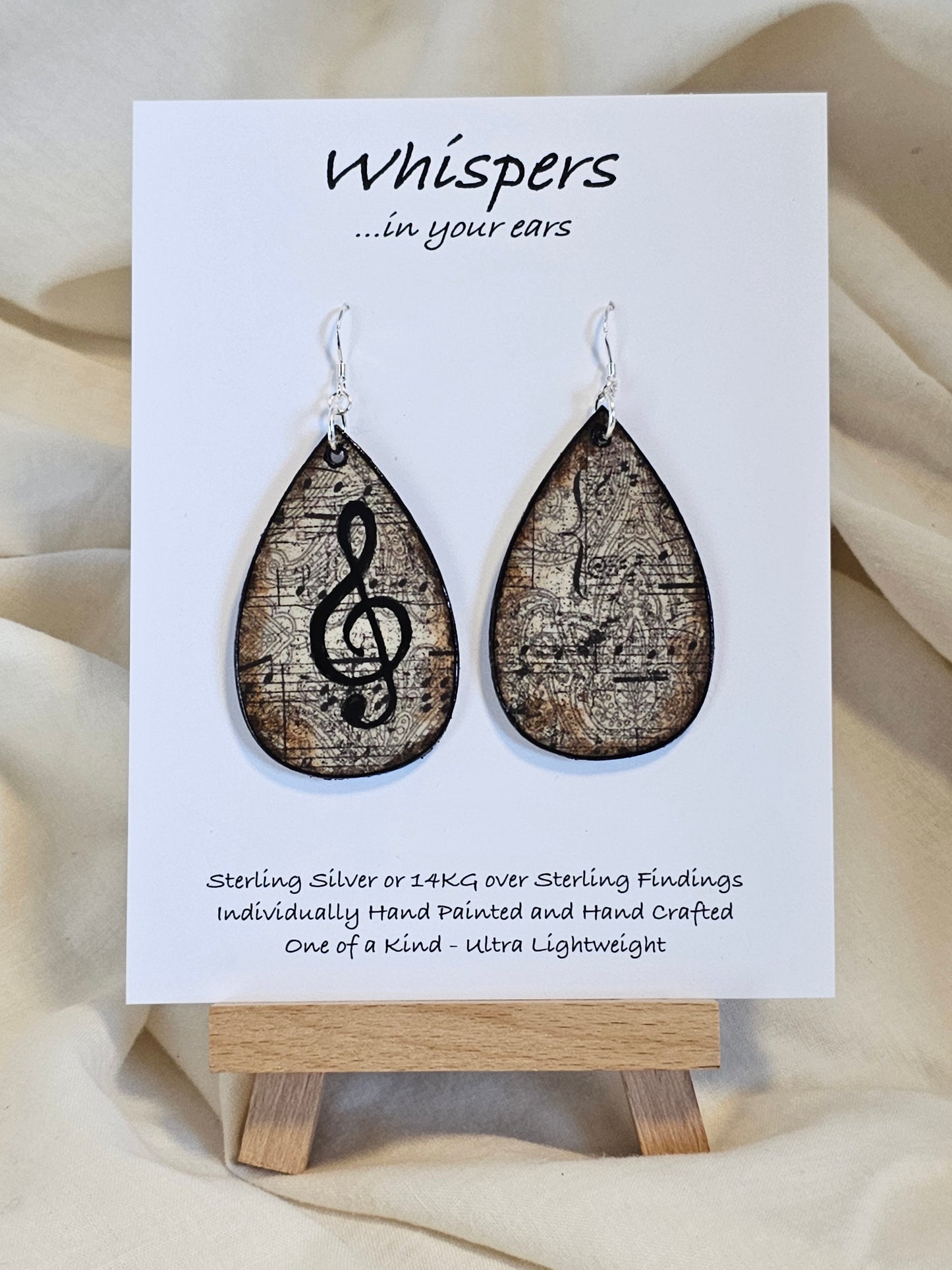Music Notes Hand Painted/Crafted Wood Earrings. 2" Wood Tear Drop with handmade paper with painted treble cleft painted Black edges. Resin Coating for durability. Back is done to compliment. Sterling silver findings. Hangs 2 1/4"