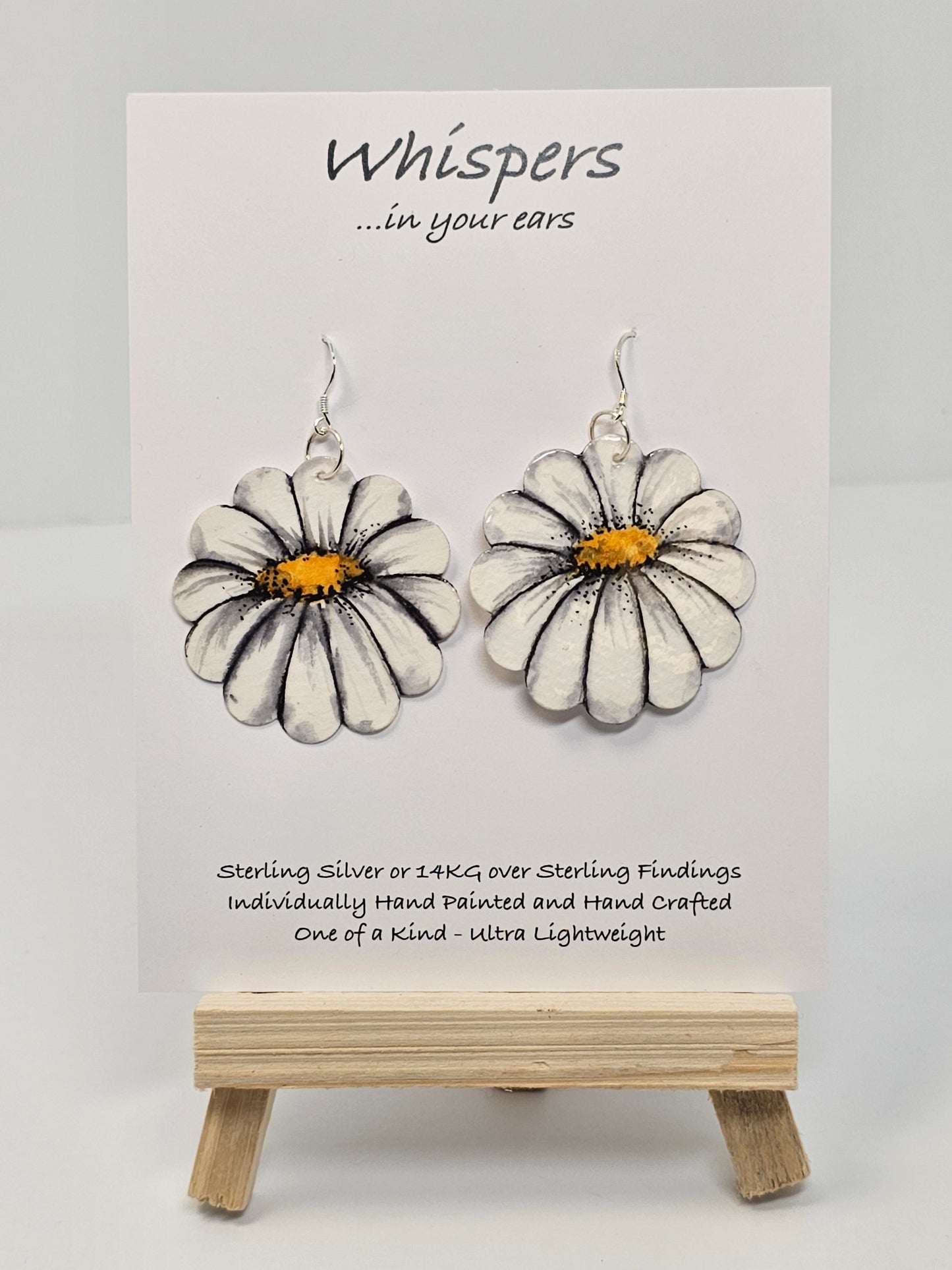 Oopsy Daisy Hand Painted Paper Earrings. Flower shaped heavy weight paper painted to resemble a white daisy with yellow center. Ultra light weight. 1 5/8" in diameter. Back of earring is painted in the same design. Resin coated for durability. Sterling silver ear wires and findings. Hangs 2"