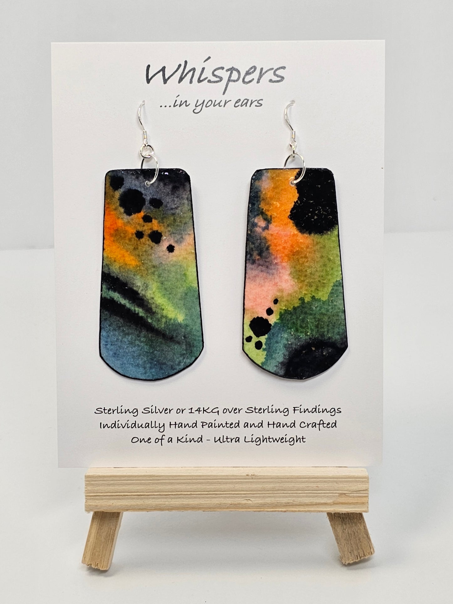 Colorful Fluid Wash Hand Painted Statement Paper Earrings. Large 2 3/4" elongated rectangle with rounded edge. Blues, oranges and black in color. Back is painted in similar design. Edged in black. Resin coated for durability. Ultra light weight. Sterling silver ear wires and findings. Hangs 3"