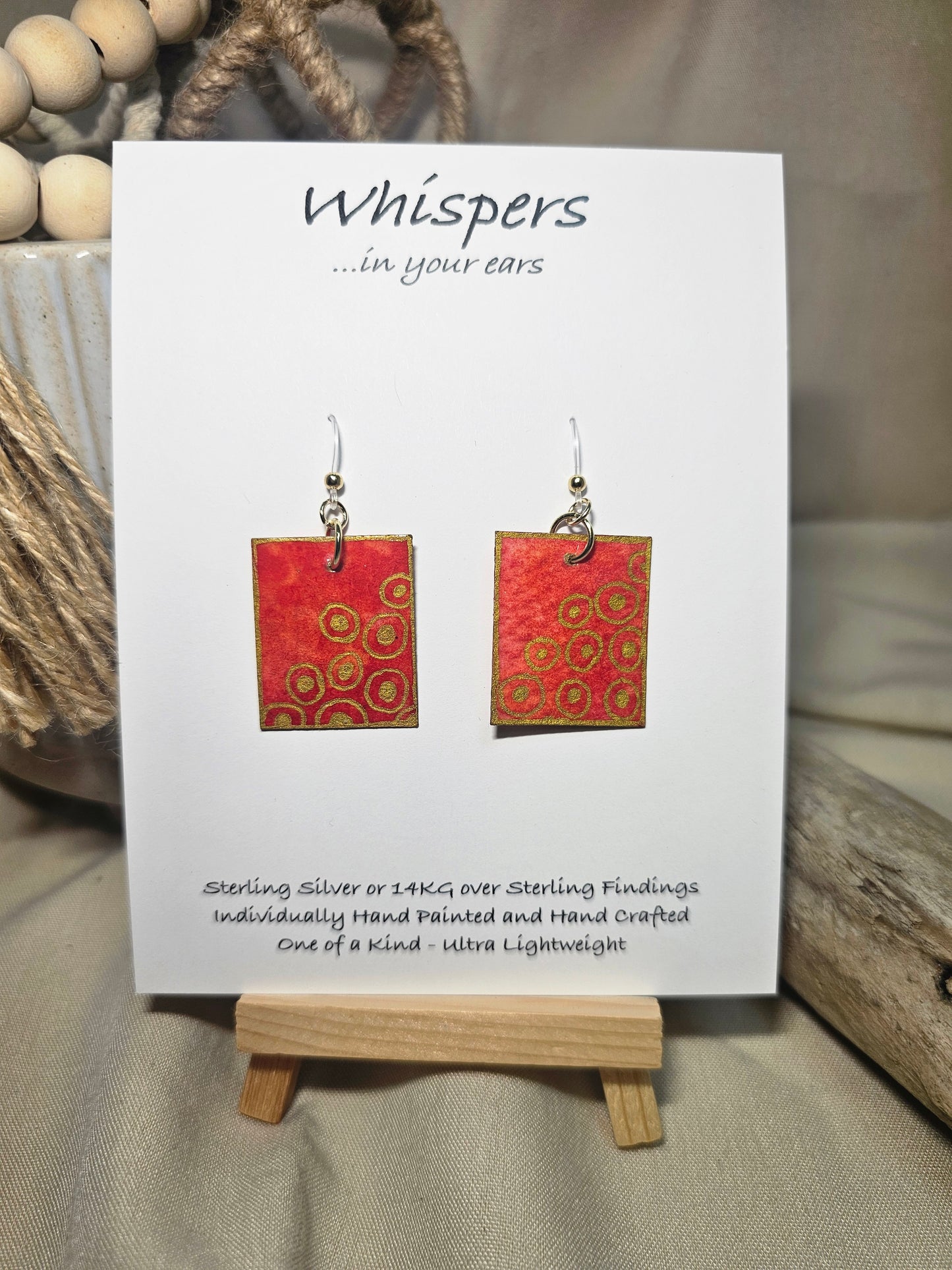 Concentric Gold Hand Painted Paper Earrings. Ultra lightweight 1" x 1 1/4" rectangle painted with Red and orange watercolor . Metallic gold circle design. Back is painted with the same design. Resin coating for durability. Acrylic ear wires. Hangs 1 1/2" in length