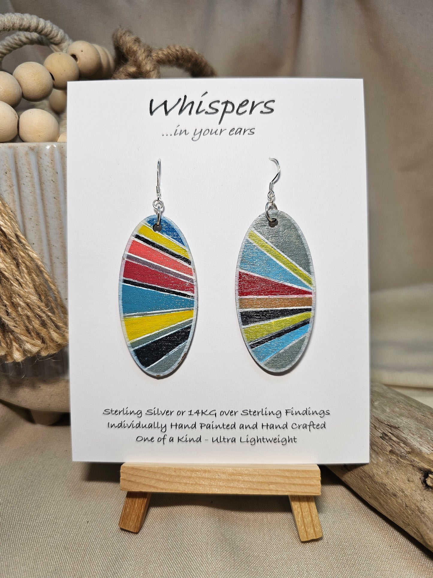Colorful Retro Sunburst Hand Painted Wood Earrings. Multicolored geometric sunburst painted in acrylics. Back is painted in similar colors and pattern. Enameled for durability. 2" Elongated wood oval. Sterling silver mixed metals with sterling silver findings and hangs 2 1/4" in length