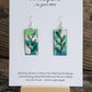 Hand painted watercolor ultra lightweight paper earrings. Blue and green background with Black linear leaf and stem design. Back is painted black. Rectangular in shape. Sterling silver findings. Hangs 1 3/4" in Length