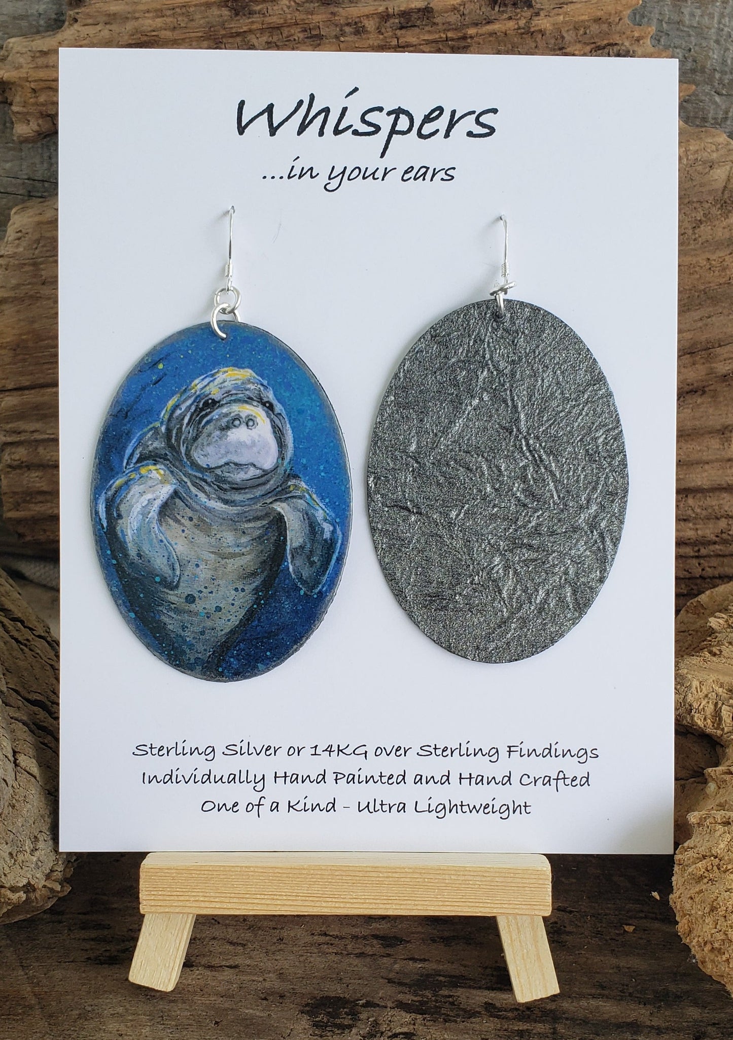 Artist print of Manatee by artist Lee M. Hein. Ultra lightweight paper earrings. Painted with silver embellishment. Back is grey iridescent textural paper. Sterling silver findings. Large statement oval in shape. Hangs 2 5/8" in Length