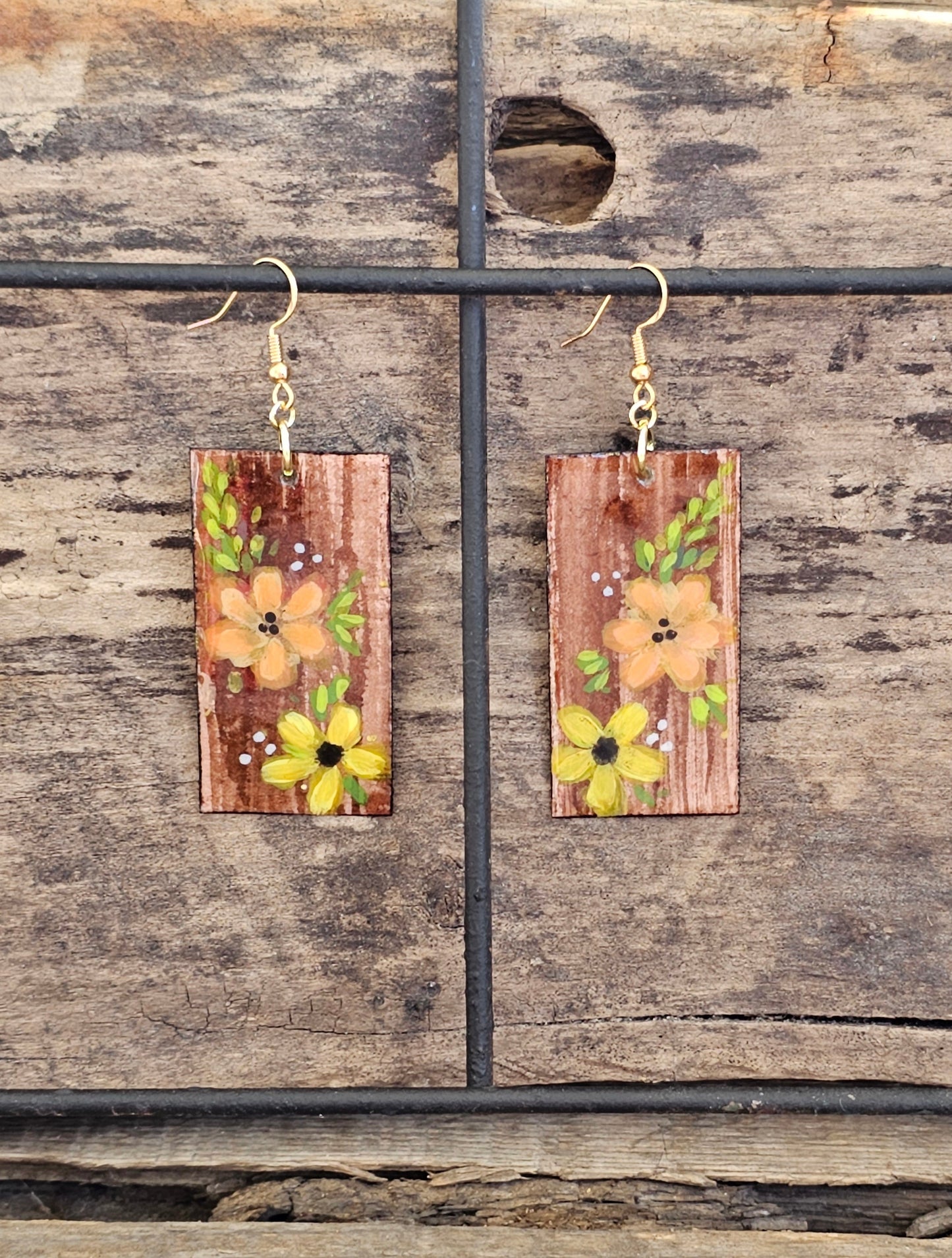 Hand painted Watercolor and Acrylic Floral Duo. Ultra lightweight paper earrings. Faux wood background with Pale yellow and Peach flowers .  Edged in brown. Back is painted in complimentary color. Rectangular in shape. 14kg over sterling silver findings. Hangs 2 1/8" in Length