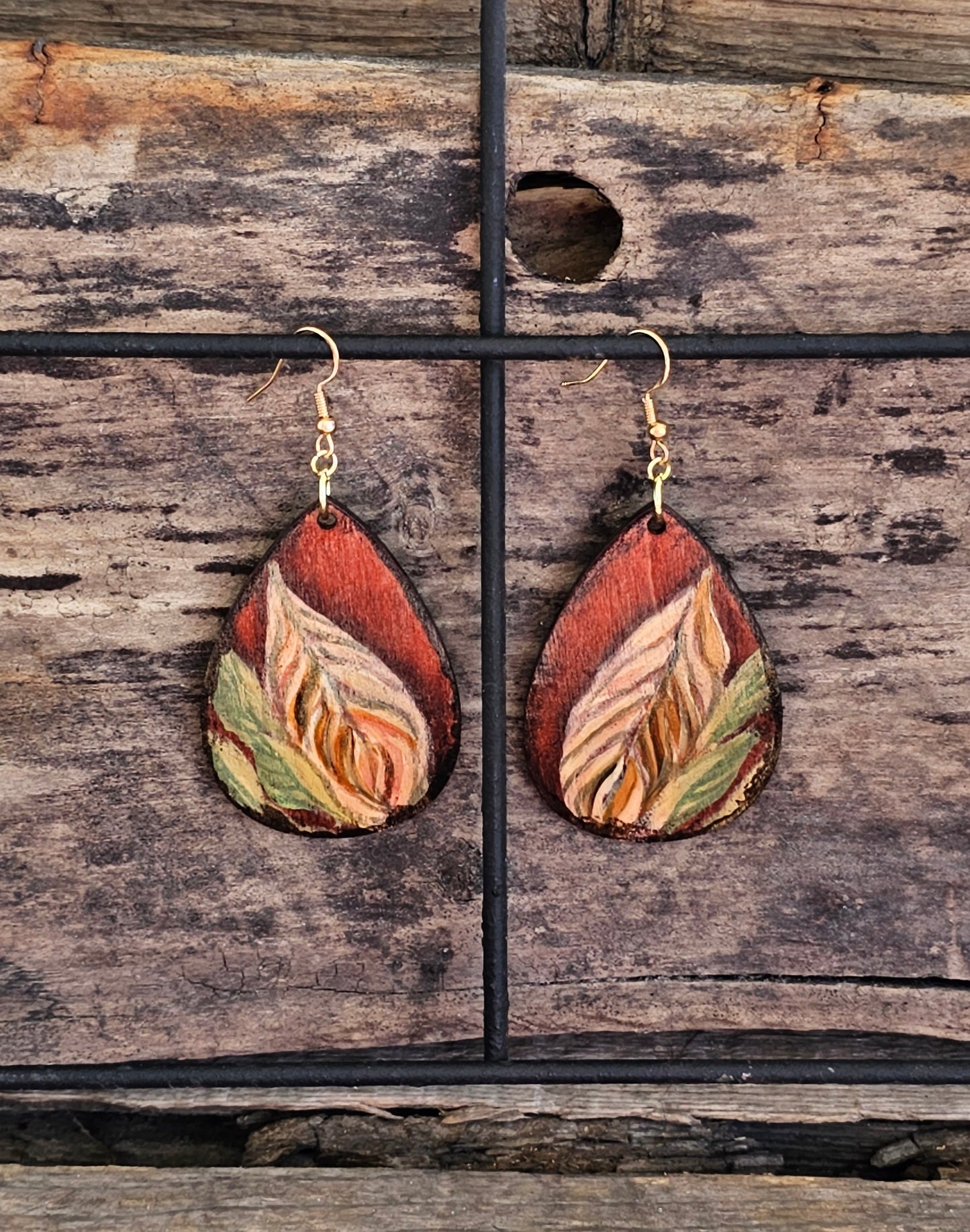 Hand Painted Ultra Lightweight Wooden Earrings. Watercolor and Acrylic. Autumn red background with tan, cream and soft green leaf design. Dark brown painted edge detail. Teardrop in shape. Back is painted in complimentary color. Sterling Silver Findings. Hangs 2 1/4" in Length