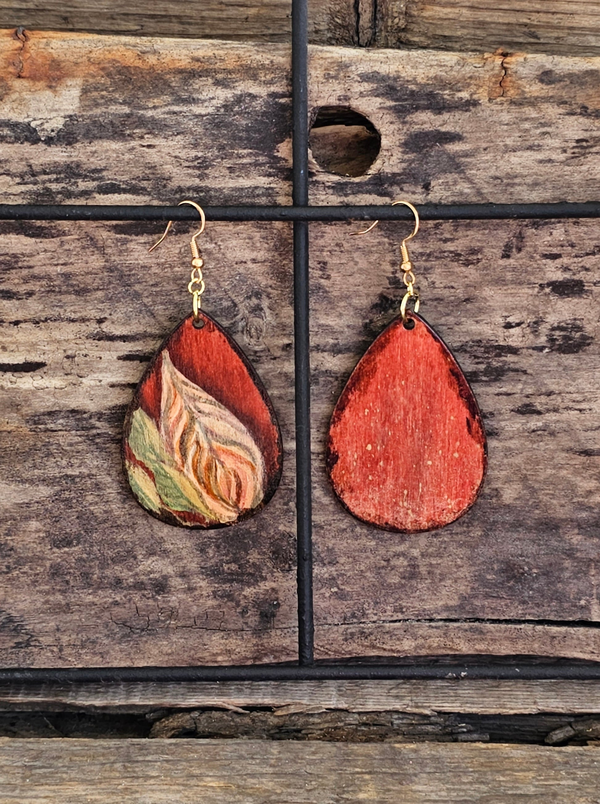 Hand Painted Ultra Lightweight Wooden Earrings. Watercolor and Acrylic. Autumn red background with tan, cream and soft green leaf design. Dark brown painted edge detail. Teardrop in shape. Back is painted in complimentary color. 14kg over Sterling Silver Findings. Hangs 2 1/4" in Length