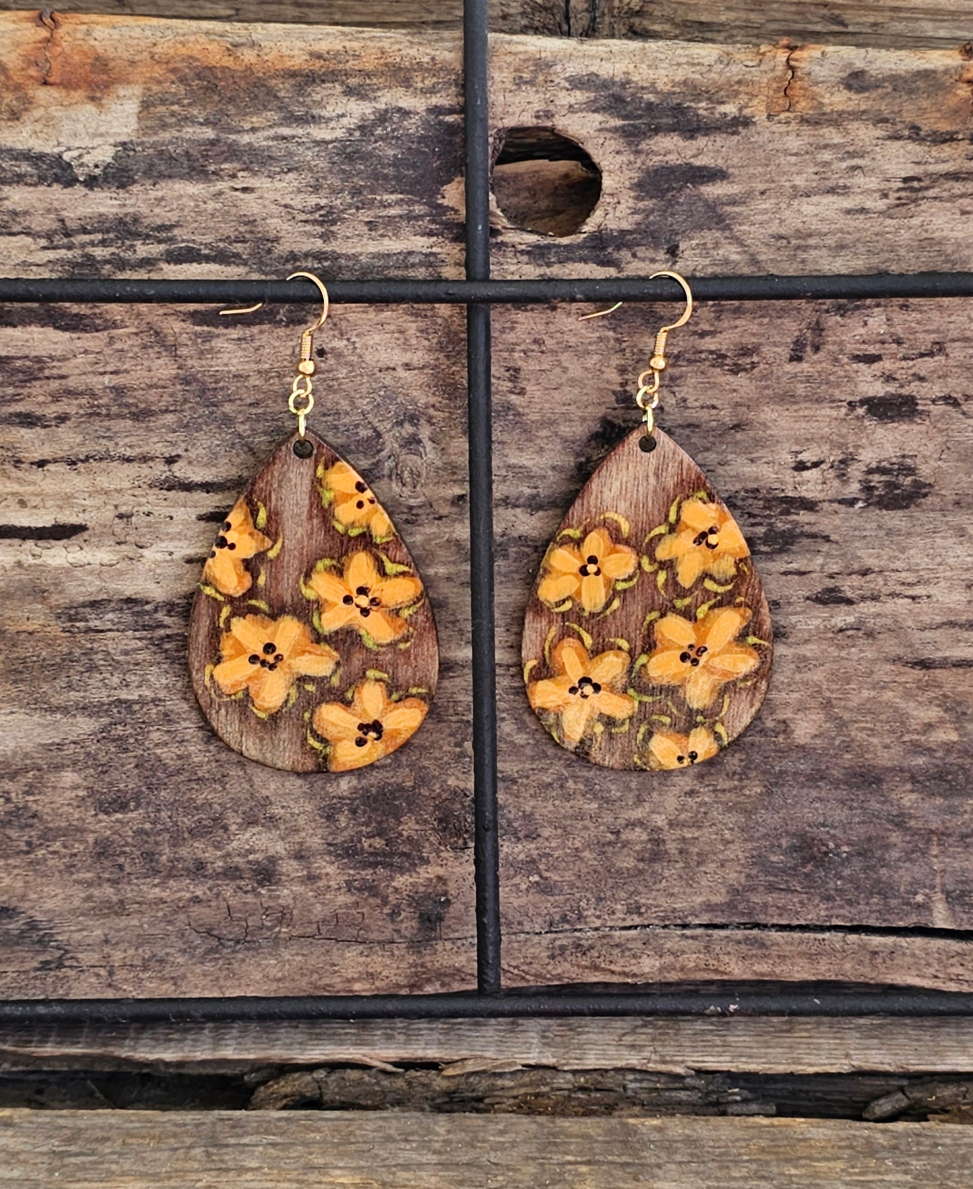 Hand Painted Ultra Lightweight Wooden Earrings. Watercolor and Acrylic.  Espresso brown washed background color with muted orange lilies painted design. Dark brown painted edge detail with accents of gold. Teardrop in shape. Back is painted in complimentary color. 14kg over Sterling Silver Findings. Hangs 2 1/4" in Length