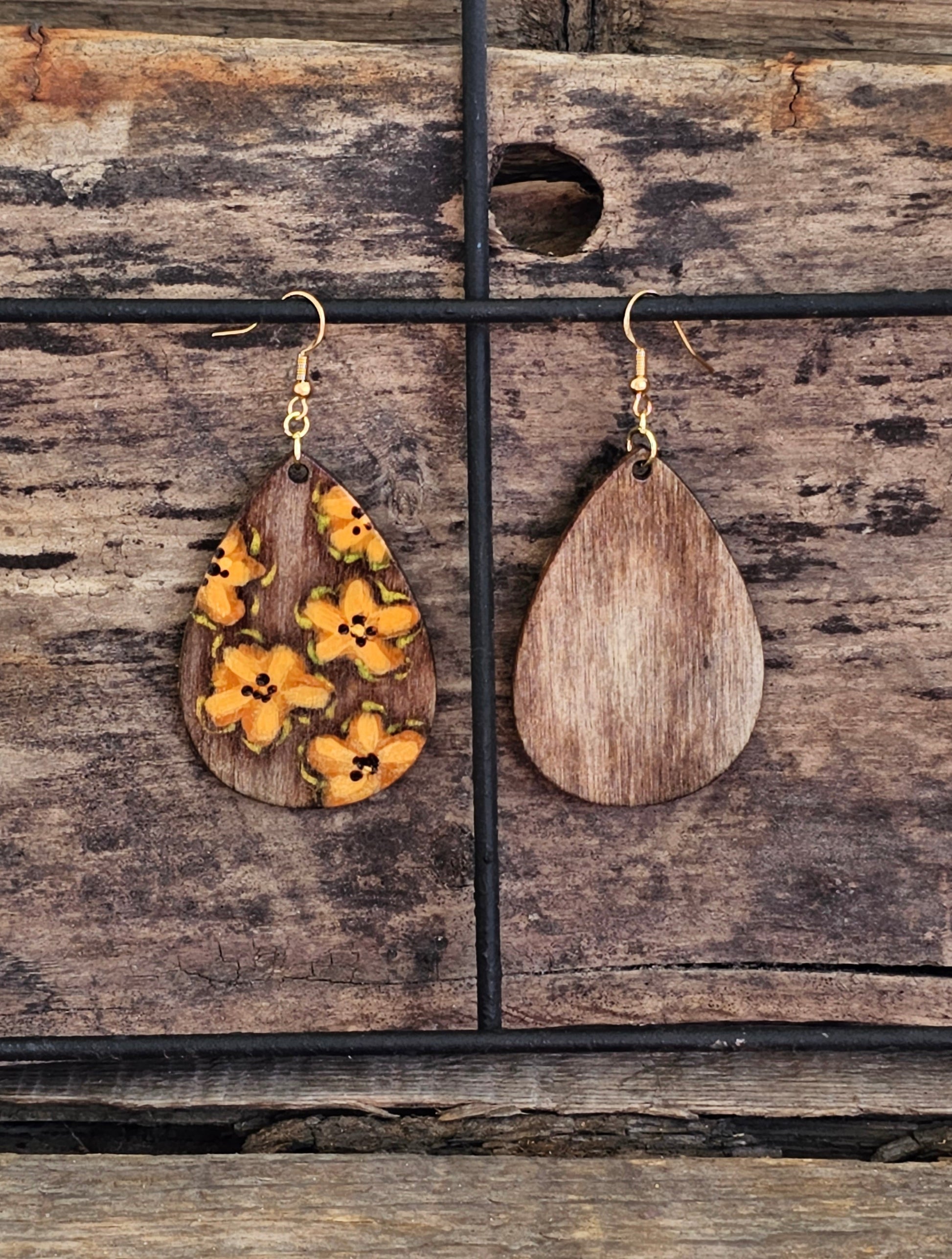 Hand Painted Ultra Lightweight Wooden Earrings. Watercolor and Acrylic.  Espresso brown washed background color with muted orange lilies painted design. Dark brown painted edge detail with accents of gold. Teardrop in shape. Back is painted in complimentary color. 14kg over Sterling Silver Findings. Hangs 2 1/4" in Length