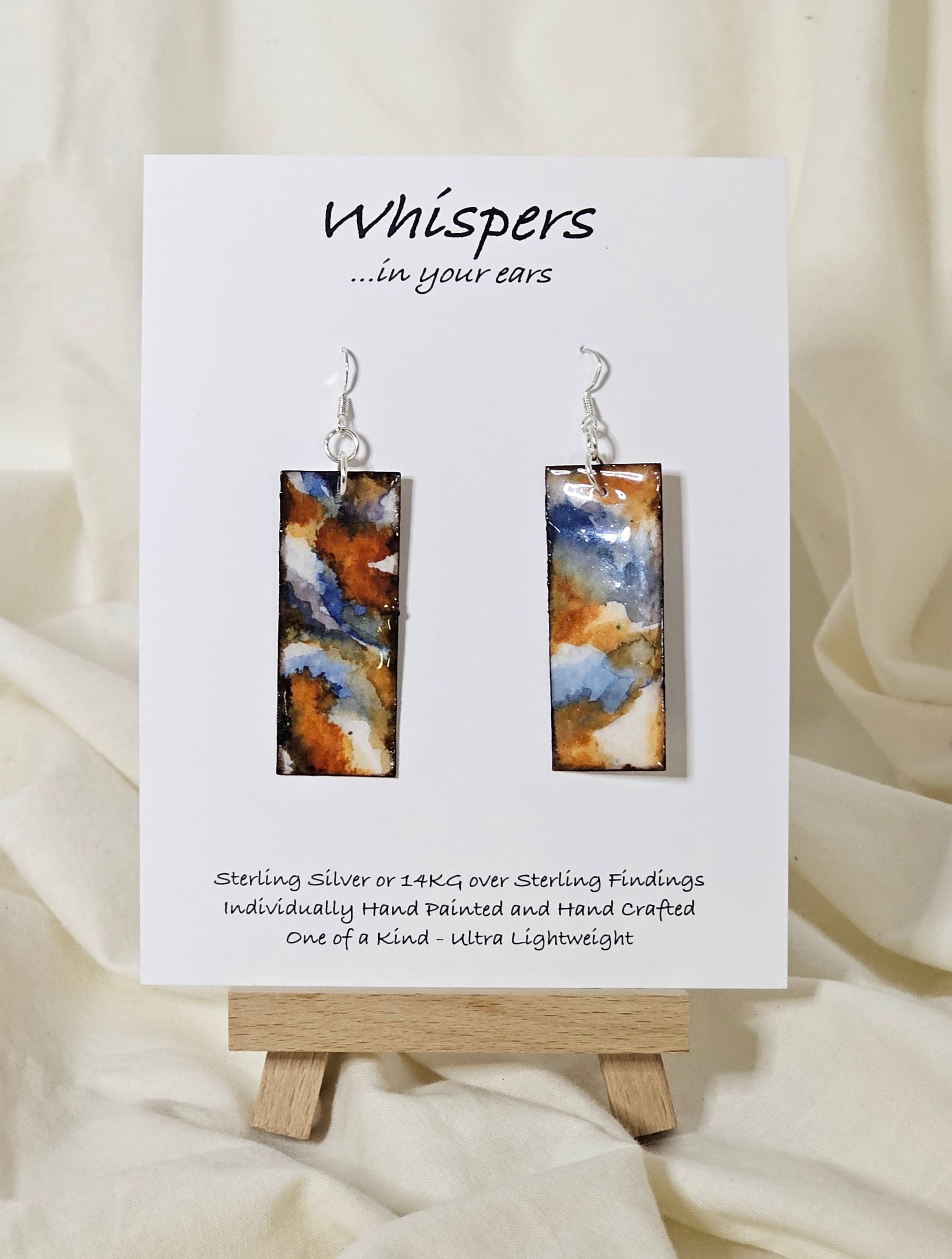 Hand painted watercolor and acrylic ultra lightweight paper earrings. Varied tones of blue, rust and brown.  Back is painted with similar design and color. Elongated rectangle in shape. Sterling silver findings. Hangs 2 1/4" in Length