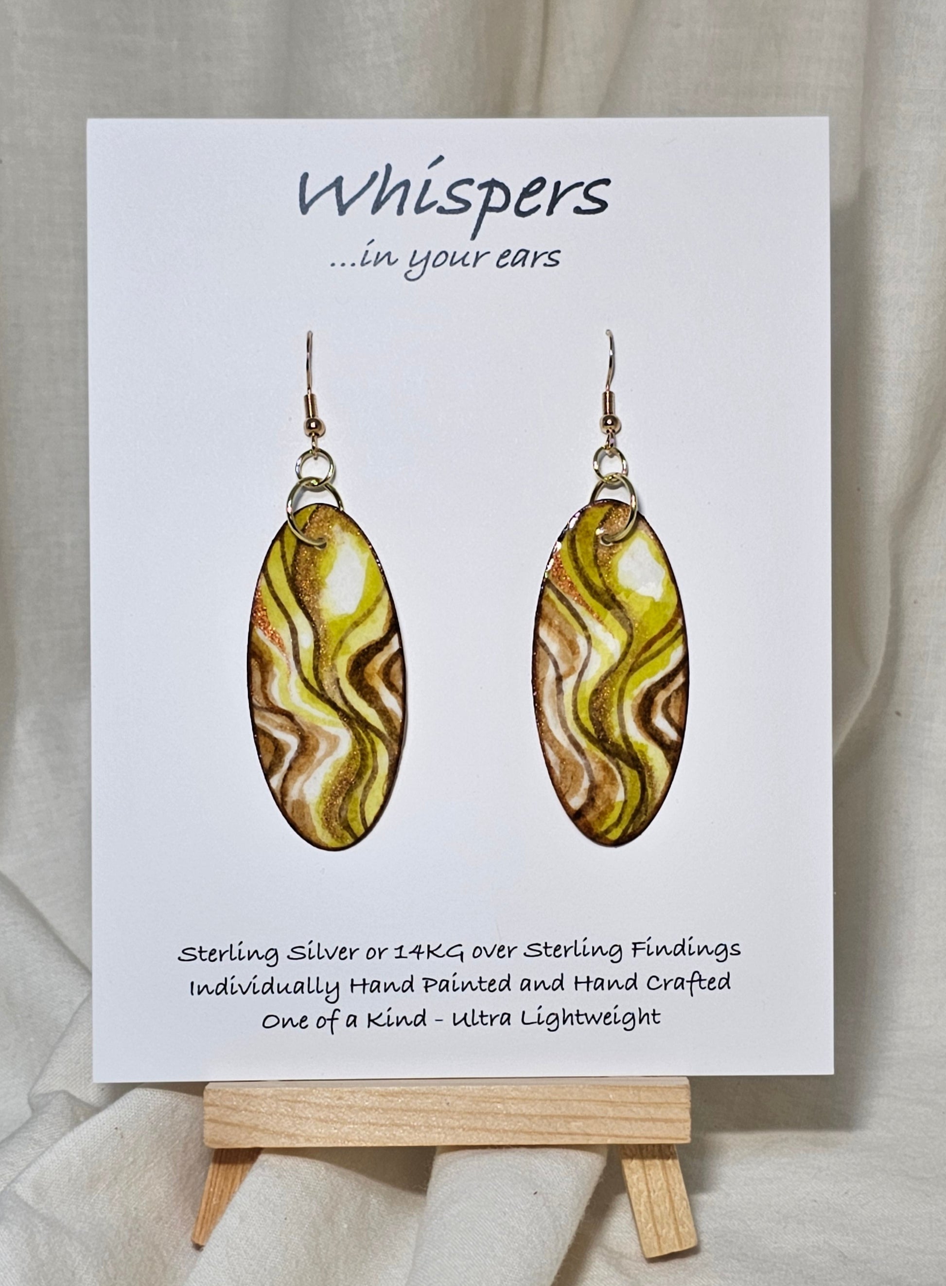Hand Painted Watercolor Paper Earrings. 2" Elongated oval, lime and moss greens accented with tans and browns in color. Copper Metallic accents. Back is painted in complimentary design. Resin coating for durability. 14KG over sterling silver findings. Hangs 2 1/4"