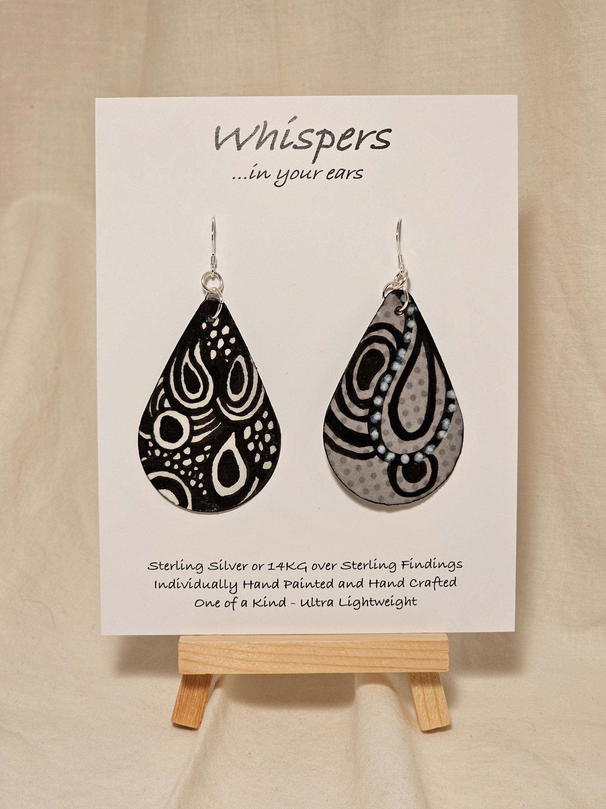 Black n White Swirls n Dots and Painted Paper Earrings. 2 1/8" Tear Drop shape. Abstract white swirls on black background. Back is Grey dots and similar design. Resin coating for durability. Sterling silver findings. Hangs 2 1/2" in length