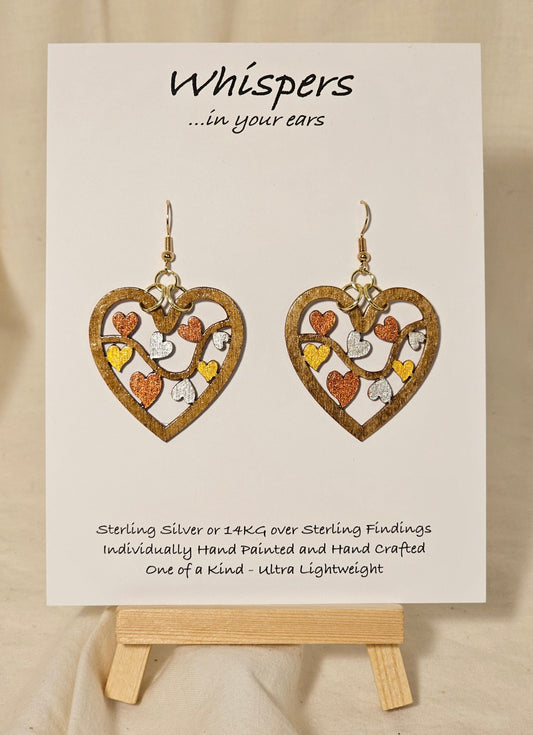 Metallic Hearts Wood Die cut hand Painted Earrings. Small hearts on a vine individually painted in gold, silver and copper. Back is painted to match. 1 1/2" Heart. Enameled for durability. 14KG over sterling findings Hangs 1 3/4" in length