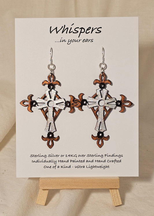 Metallic Iron Cross Hand Painted Statement Wood Cross. Painted in Silver, Bronze and Iron Black. Fleur-de-lis die cut details. 2 5/8" Cross. Back is painted to match. Enameled for durability. Sterling Silver findings. Hangs 3" in length