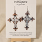Metallic Iron Cross Hand Painted Statement Wood Cross. Painted in Silver, Bronze and Iron Black. Fleur-de-lis die cut details. 2 5/8" Cross. Back is painted to match. Enameled for durability. Sterling Silver findings. Hangs 3" in length