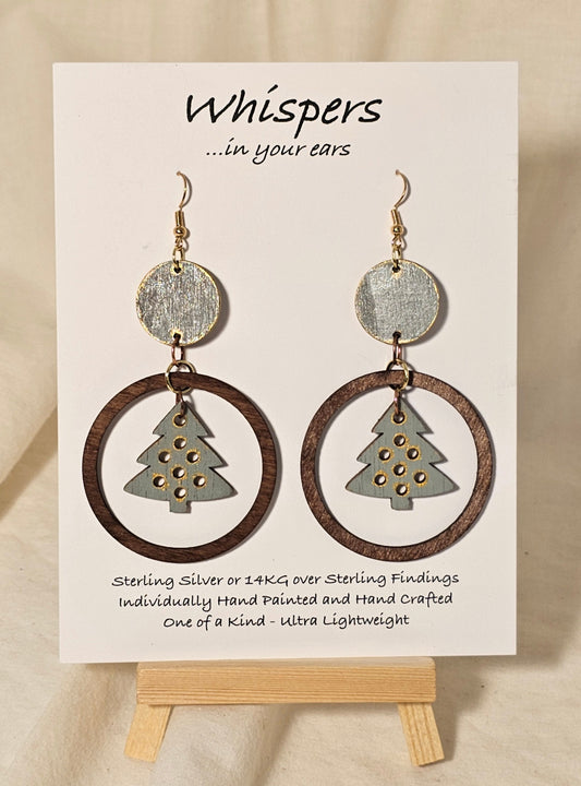 Christmas Tree Hand Painted Wood Earrings. Sage green, walnut and gold large statement piece. Wood disk, open wood circle with hanging wooden tree pendant. Back is painted to match. Enameled for durability. 14KG over sterling findings. Hangs 3" in length.