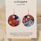 Poinsettia Embossed Repurposed Card Paper Earrings. 1 3/4" Circle edge painted and embellished with white texture. Back is complimentary design. Resin coating for durability. Sterling Silver findings. Hangs 2" in length