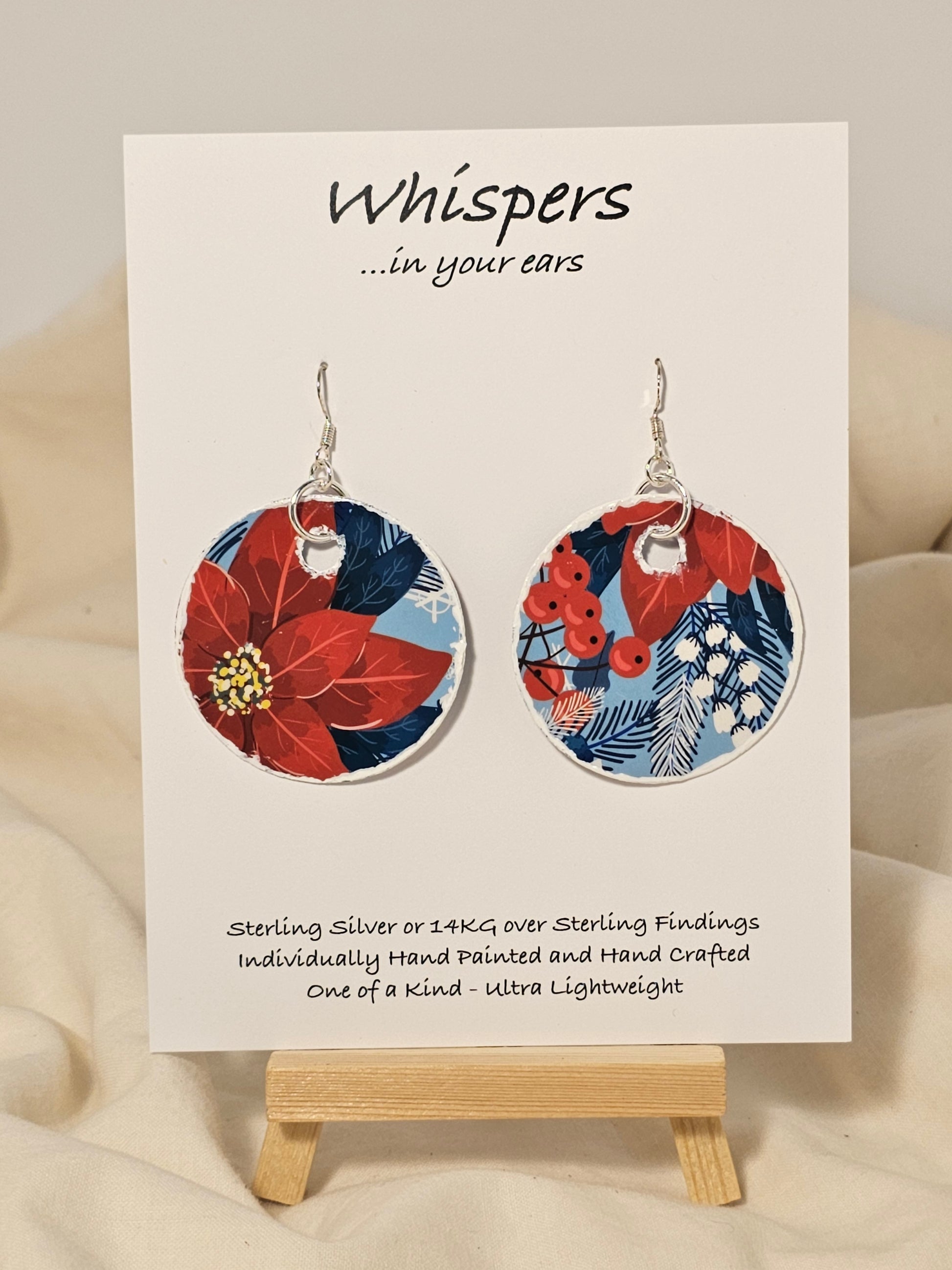 Poinsettia Embossed Repurposed Card Paper Earrings. 1 3/4" Circle edge painted and embellished with white texture. Back is complimentary design. Resin coating for durability. Sterling Silver findings. Hangs 2" in length
