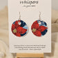 Poinsettia Embossed Repurposed Card Paper Earrings. 1 3/4" Circle edge painted and embellished with white texture. Back is complimentary design. Resin coating for durability. Sterling Silver findings. Hangs 2" in length