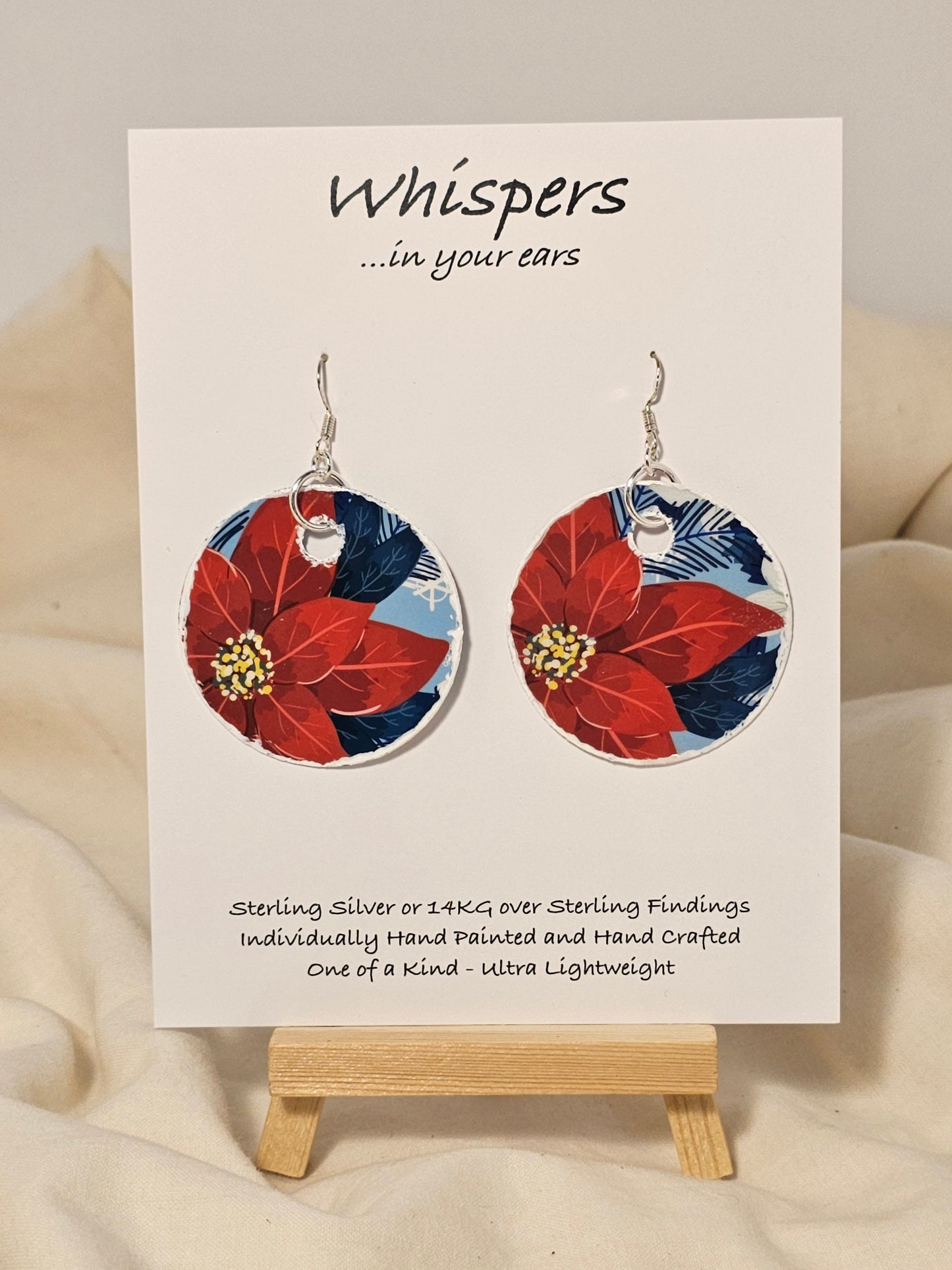 Poinsettia Embossed Repurposed Card Paper Earrings. 1 3/4" Circle edge painted and embellished with white texture. Back is complimentary design. Resin coating for durability. Sterling Silver findings. Hangs 2" in length