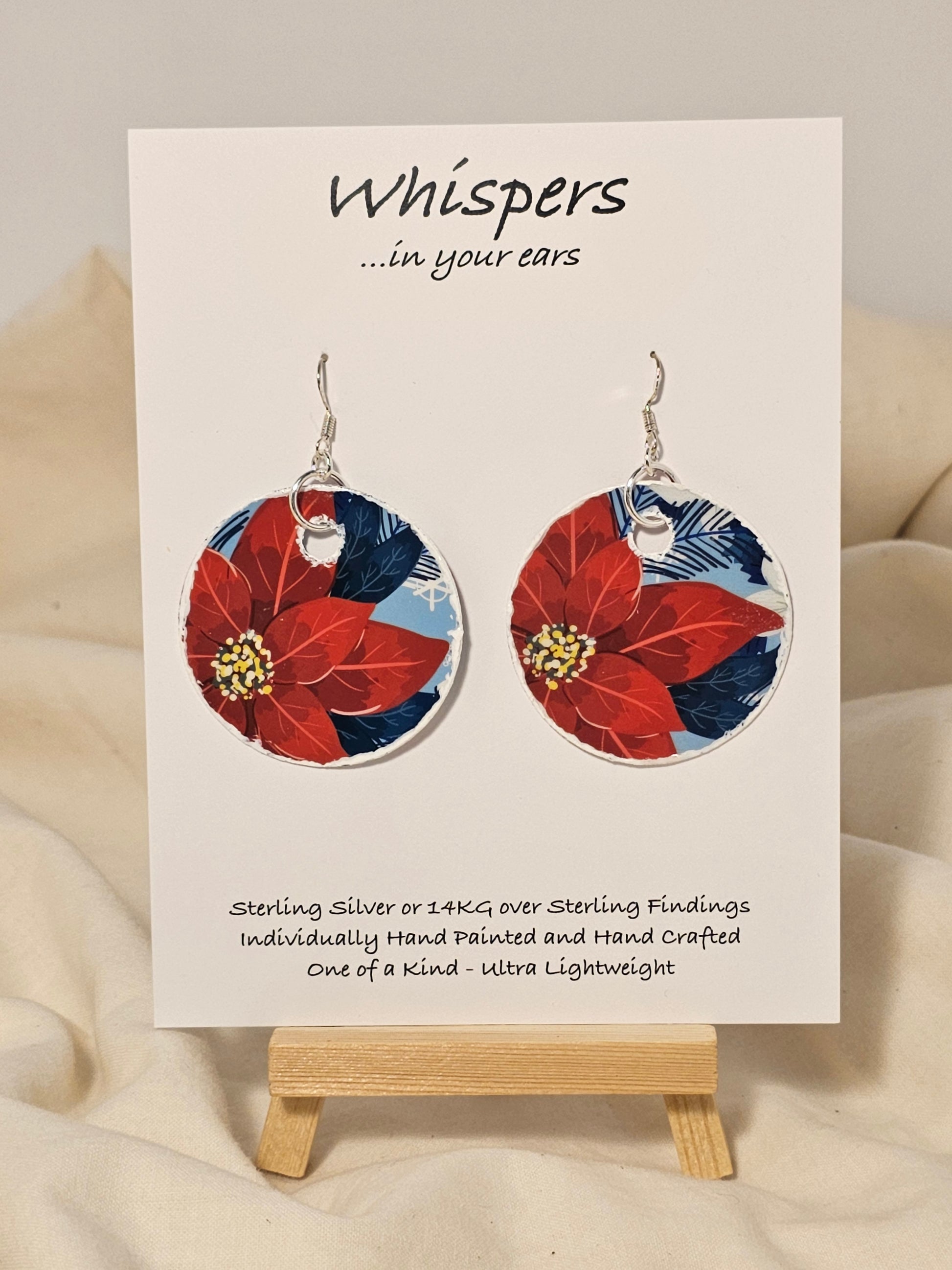 Poinsettia Embossed Repurposed Card Paper Earrings. 1 3/4" Circle edge painted and embellished with white texture. Back is complimentary design. Resin coating for durability. Sterling Silver findings. Hangs 2" in length
