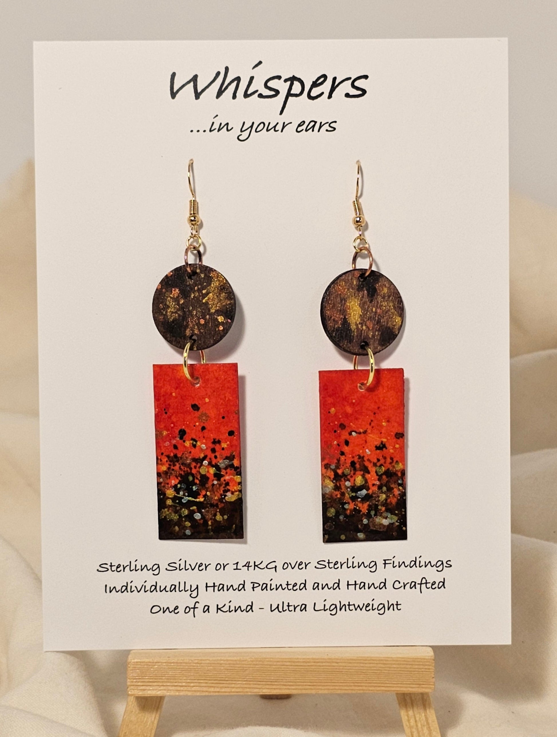 Metallic Confetti Hand Painted Paper and Wood Earrings. Paper hand painted Red with metallic accents. Hanging from embellished wooden disc. Back is painted to match. Resin coating for durability. Mixed metal findings. 14KG over sterling ear wires. Hangs 2 3/4" in length