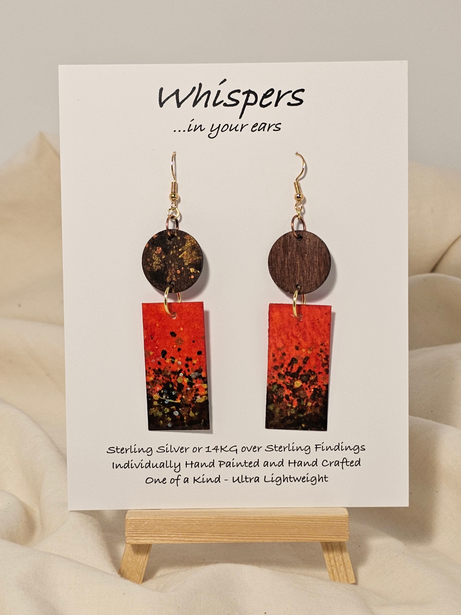 Metallic Confetti Hand Painted Paper and Wood Earrings. Paper hand painted Red with metallic accents. Hanging from embellished wooden disc. Back is painted to match.&nbsp; Resin coating for durability. Mixed metal findings. 14KG over sterling ear wires. Hangs 2 3/4" in length