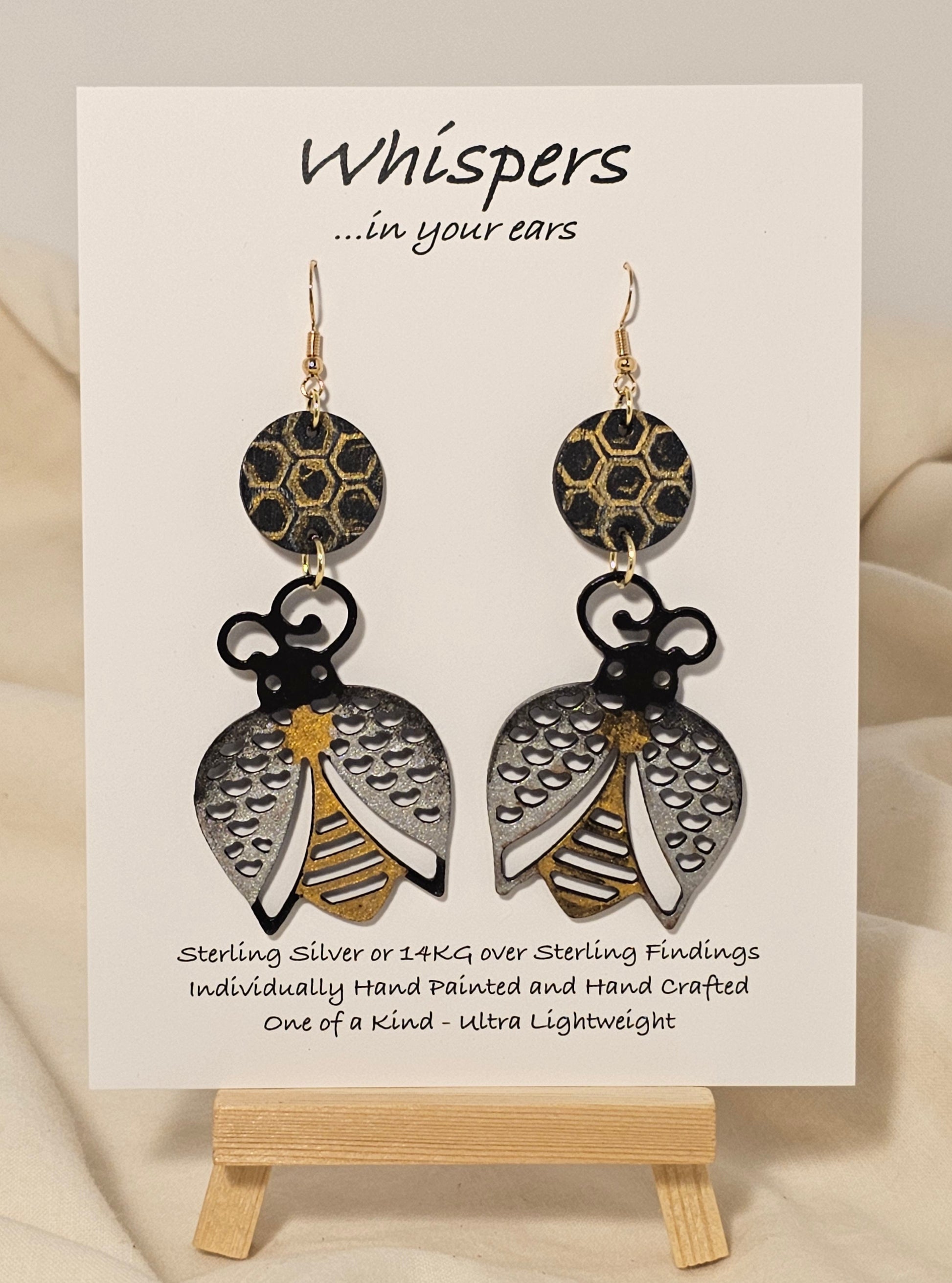 Bee Golden Wood Die Cut Hand Painted Earrings. Honeycomb in gold and black painted wood disc. Metallic painted bee wood die cut. Back is painted to match. Enameled for durability. 14KG over sterling silver findings. Hangs 3" in length