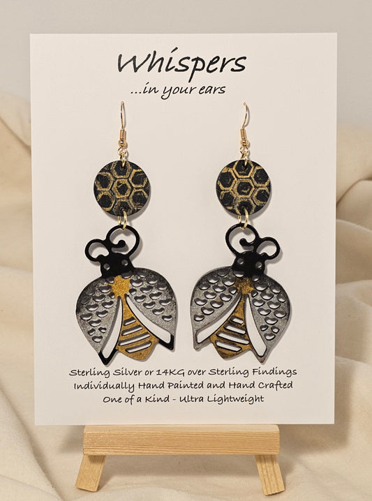 Bee Golden Wood Die Cut Hand Painted Earrings. Honeycomb in gold and black painted wood disc. Metallic painted bee wood die cut. Back is painted to match. Enameled for durability. 14KG over sterling silver findings. Hangs 3" in length