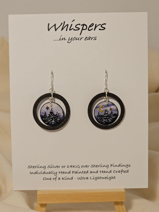 Evening Winter Scape Wood and Paper Earrings. 1 1/8" wood ring painted black. Hanging hand painted watercolor tree silhouette winter scape. Embellished with golden moon. Back is painted with complimentary design. Resin coating for durability. Sterling silver findings. Hangs 1 3/8" in length