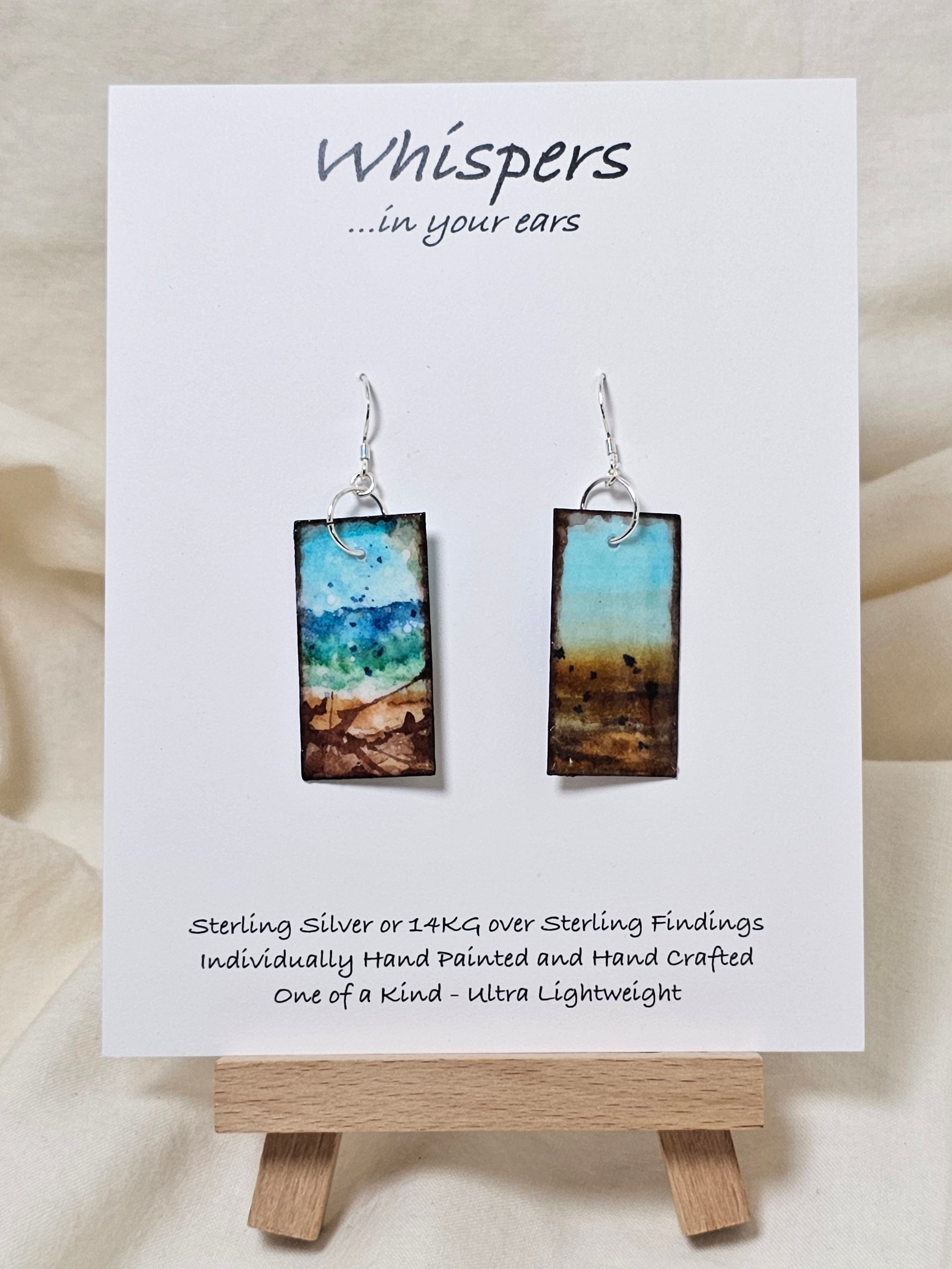 Blowing Ocean Scape Hand Painted Paper Earrings. Ultra lightweight ! 1/2" Rectangle painted in watercolor. Abstract ocean scape. Aqua, blues and browns. Back is painted similar design. Resin coating for durability. Sterling silver findings. Hangs 1 3/4" in length