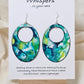 Caribbean Waters Hand Painted Paper Earrings. Ultra lightweight 2 1/2" Statement Oval with medium circular cut out. Watercolor blues, greens and turquoise. Abstract design. Back is painted in similar colors. Resin coating for durability. Sterling Silver findings. Hangs 2 3/4" in length