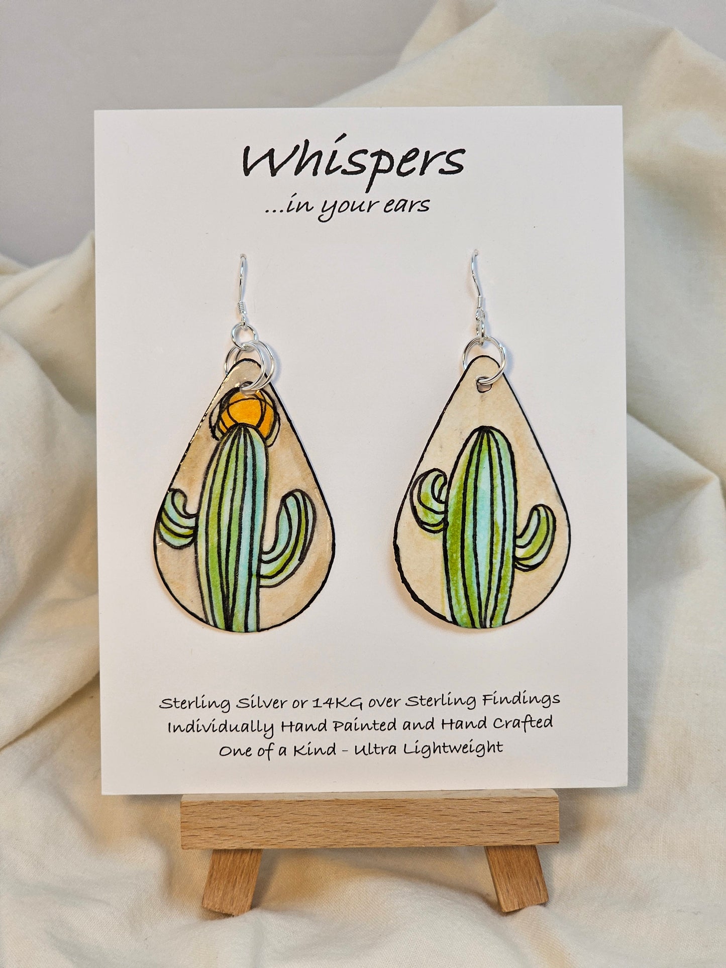Abstract Sun and Cactus hand painted watercolor paper earrings. Ultra lightweight. Tans and Muted greens. Black painted edge detail. Back is painted with similar colors and design. Tear drop in shape. Resin coating for durability. Double Jump ring detail. Sterling silver findings. Hangs 2 1/4" in length