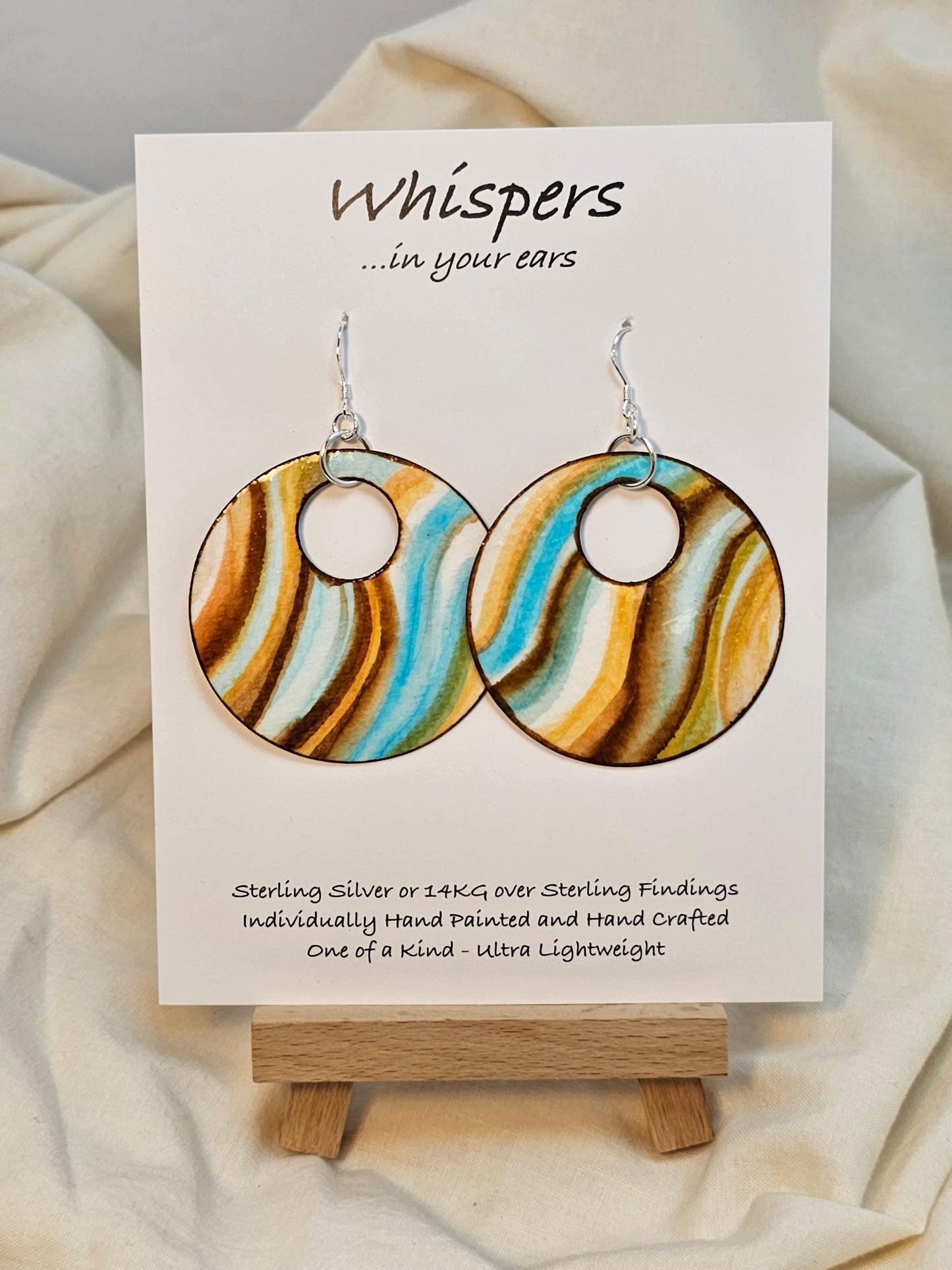 Waves of Peach Hand painted watercolor ultra lightweight paper earrings. 2" circle painted Aqua blue, peach and brown on white background. Dark brown detail painted edge. Back is painted with similar color and design. Large circular in shape with circular cut out. Resin coating for durability. Sterling silver findings. Hangs 2 1/4" in length