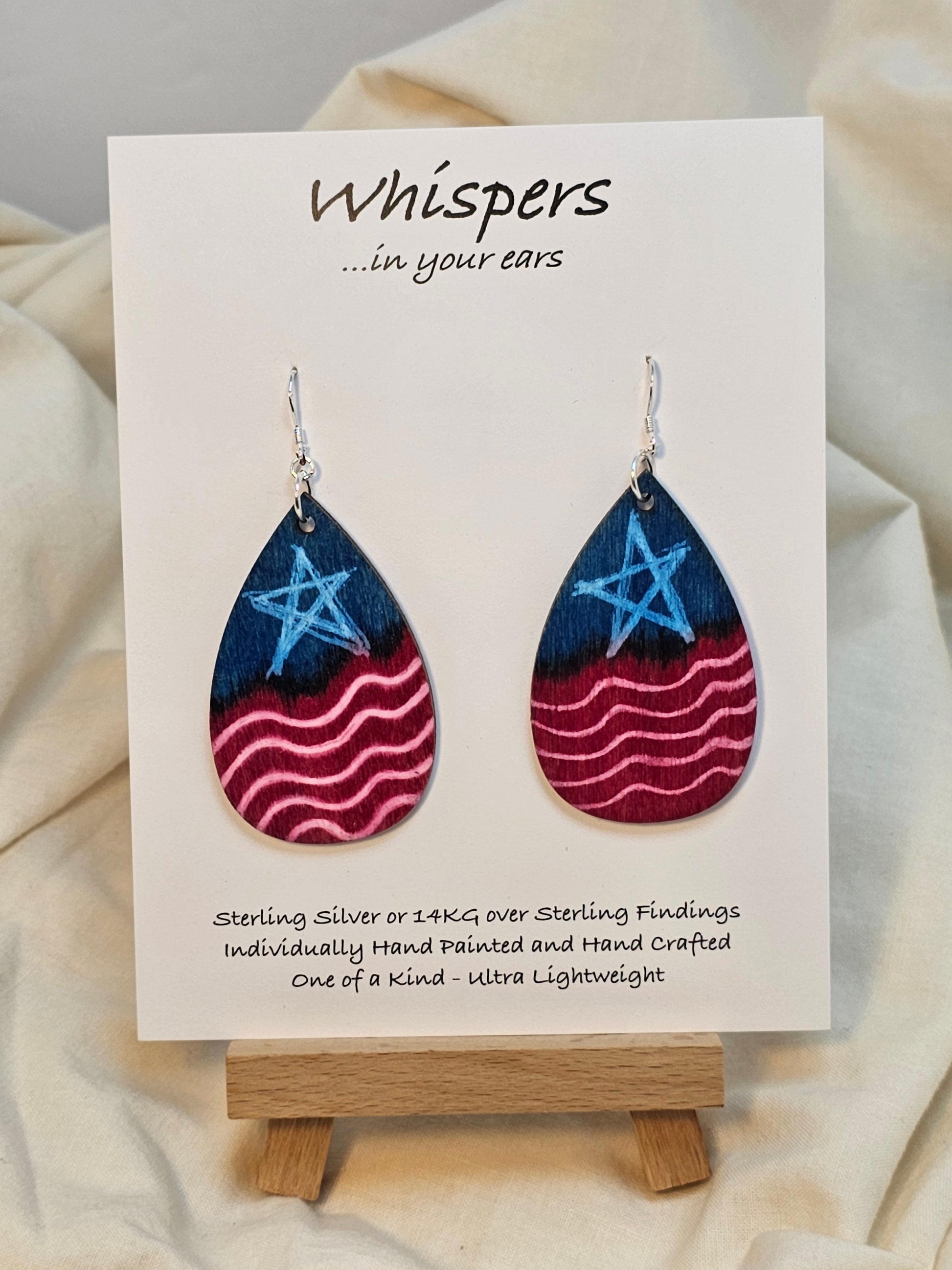 Americana Wood Earrings. 2" Tear drop. Painted in watercolor and acrylic stars and stripes. Red, white and blue. Back is painted to match. Enameled for durability. Sterling silver findings. Hangs 2 1/4" in length